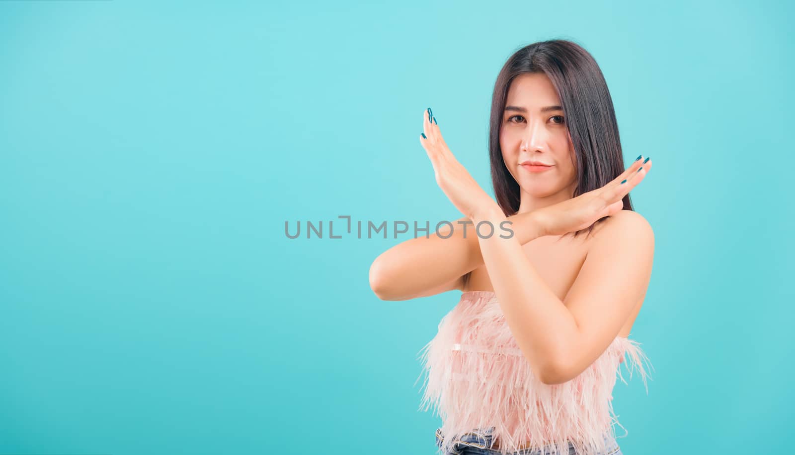 Asian beautiful woman her showing say no hand sign looking to camera on blue background, with copy space for text