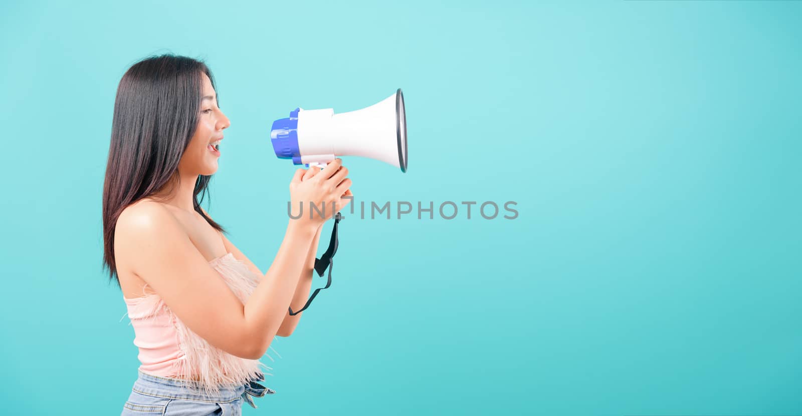 Smiling face portrait asian beautiful woman her usring megaphone on blue background, with copy space for text