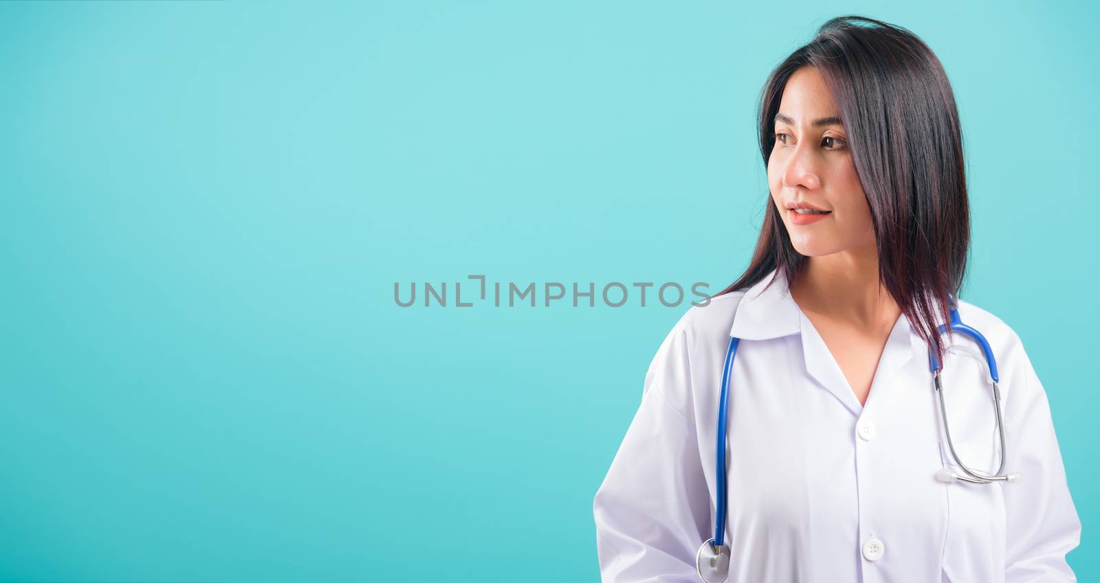 Portrait asian beautiful doctor woman smiling her standing with Hands in Pockets on blue background, with copy space for text