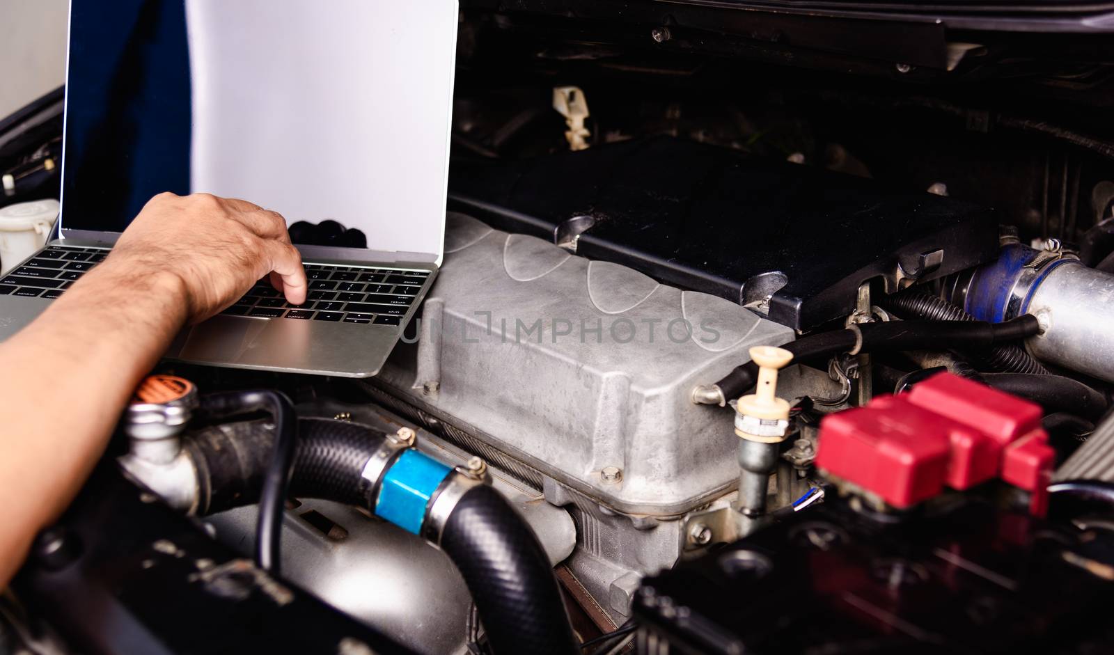 Professional car repair or maintenance mechanic engine working service with laptop computer at workshop