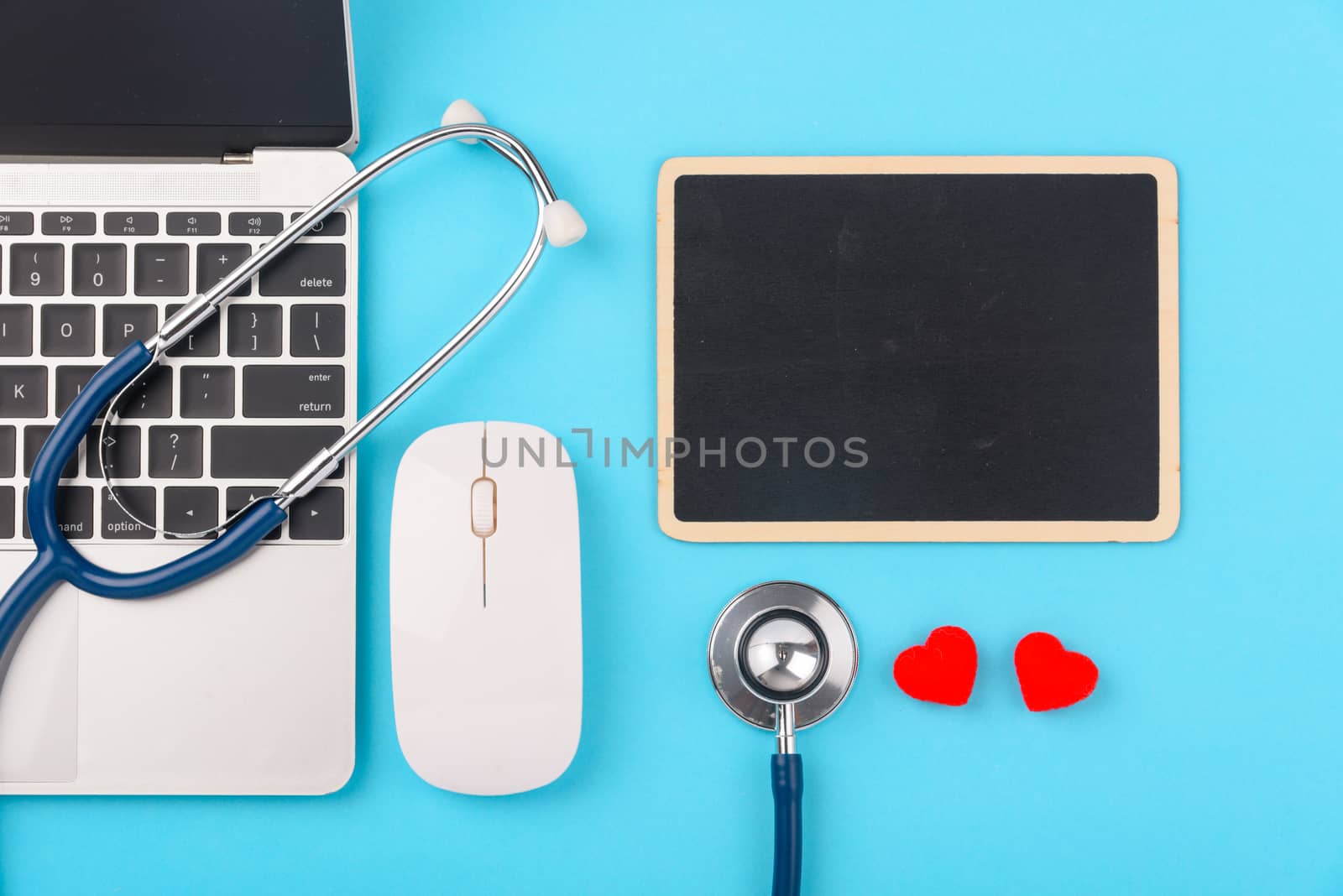 Doctor's Day concept, flat lay top view, stethoscope with laptop computer and black board diagnosis of heart disease on blue background with copy space for text