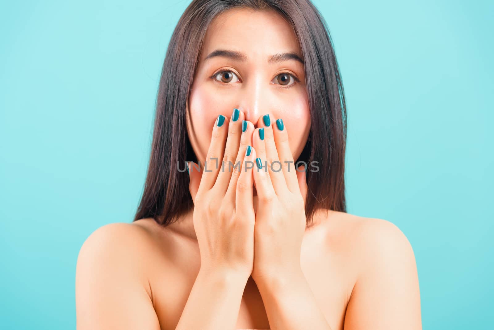 Asian beautiful woman her shocked or surprised her use hands close mouth staring eyes look camera on blue background, with copy space for text