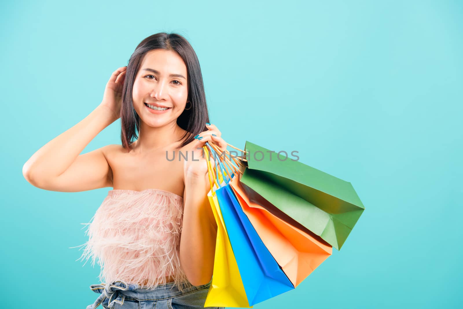 Portrait asian beautiful woman happy smiling her holding shopping bags on blue background, with copy space for text