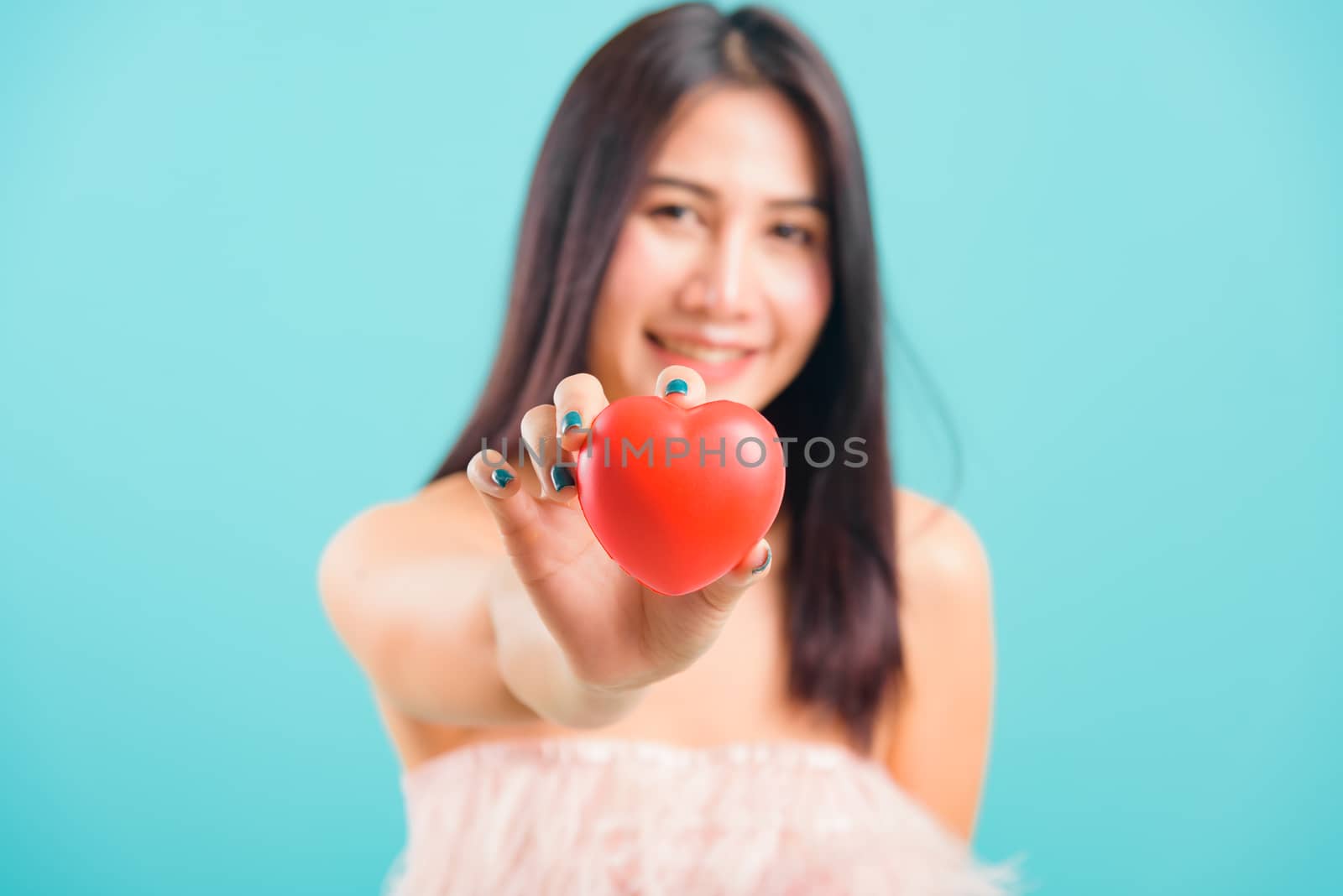 Portrait asian beautiful woman smiling her Stick out red heart on hand focus heart on blue background, with copy space for text