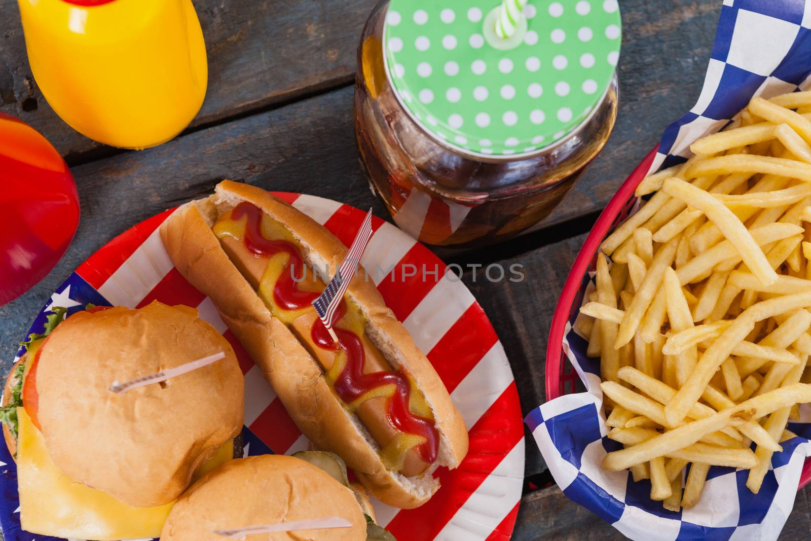 Close-up of snacks and cold drink on wooden table with 4th july theme
