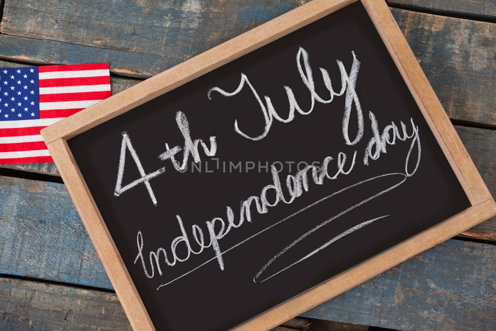 American flag and slate with text 4th july independence day by Wavebreakmedia