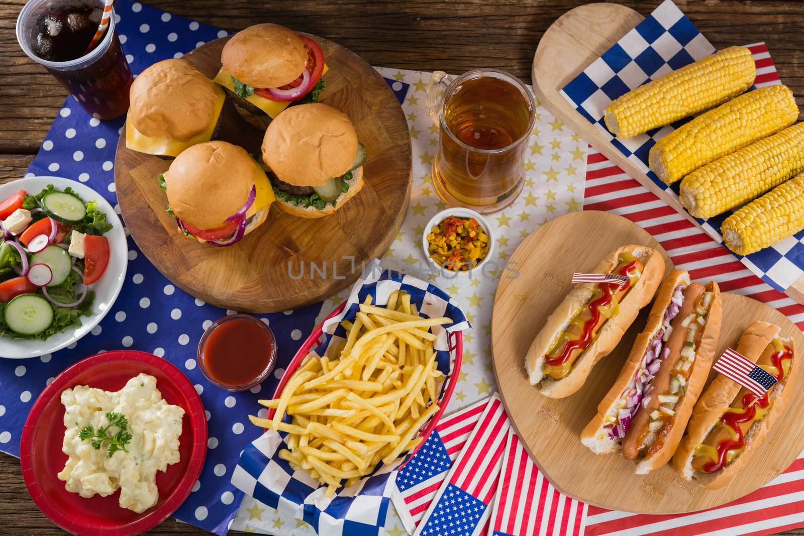 Hot dogs and burgers on wooden table with 4th july theme by Wavebreakmedia