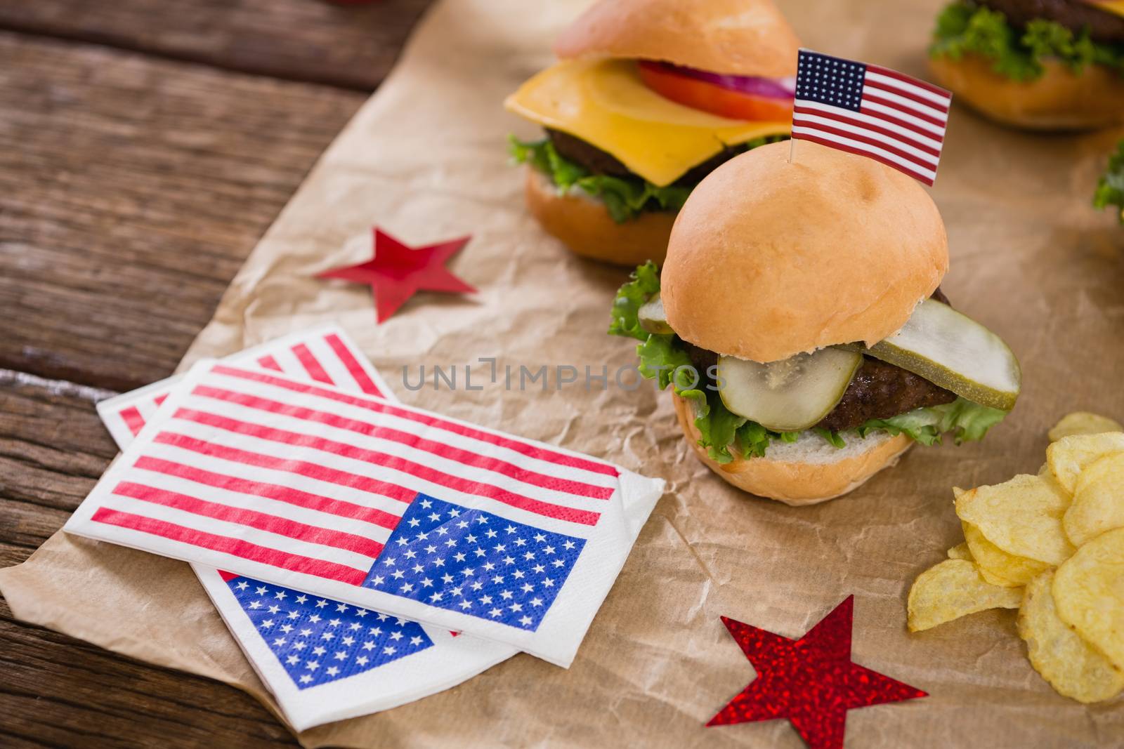 Burger and potato chips decorated with 4th july theme on wooden table
