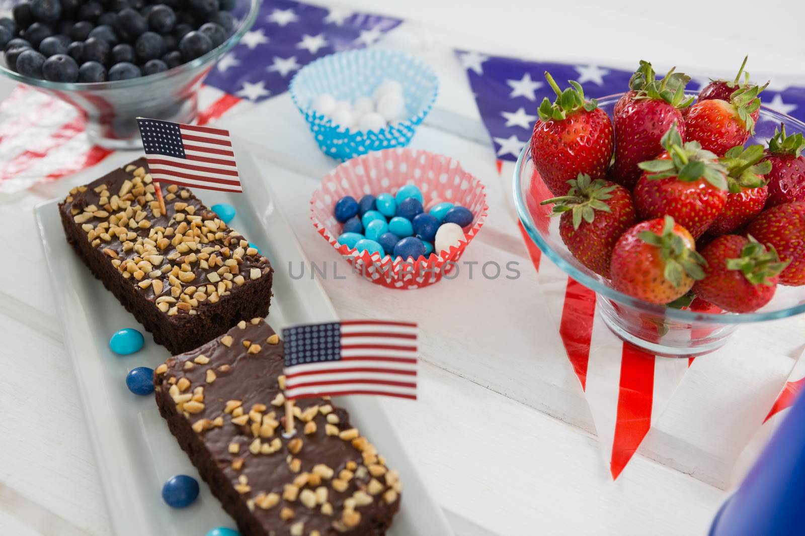 Close-up of sweet food and strawberries decorated with 4th july theme on wooden table