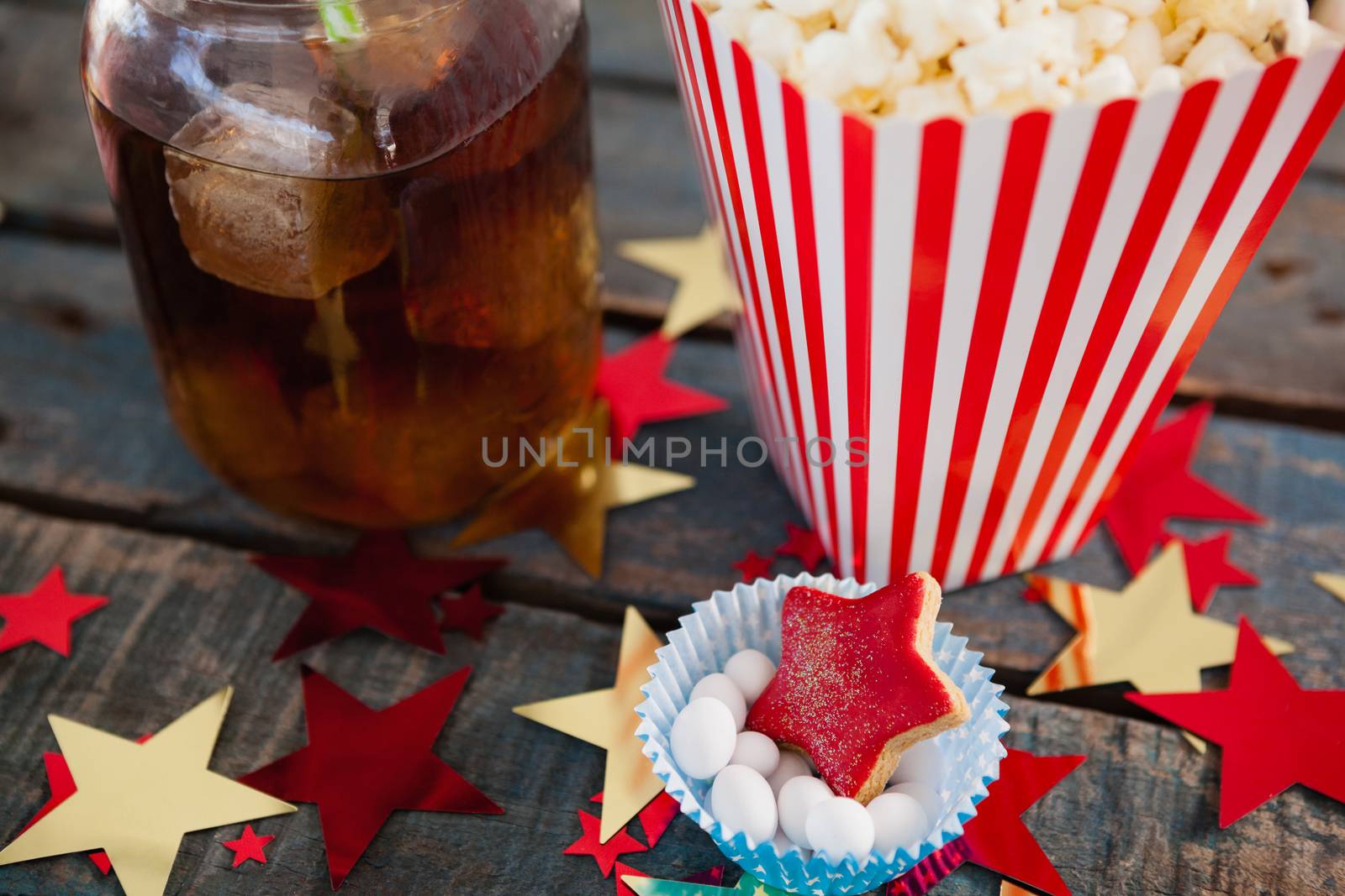 Popcorn, confectionery and drink with 4th july theme on wooden table
