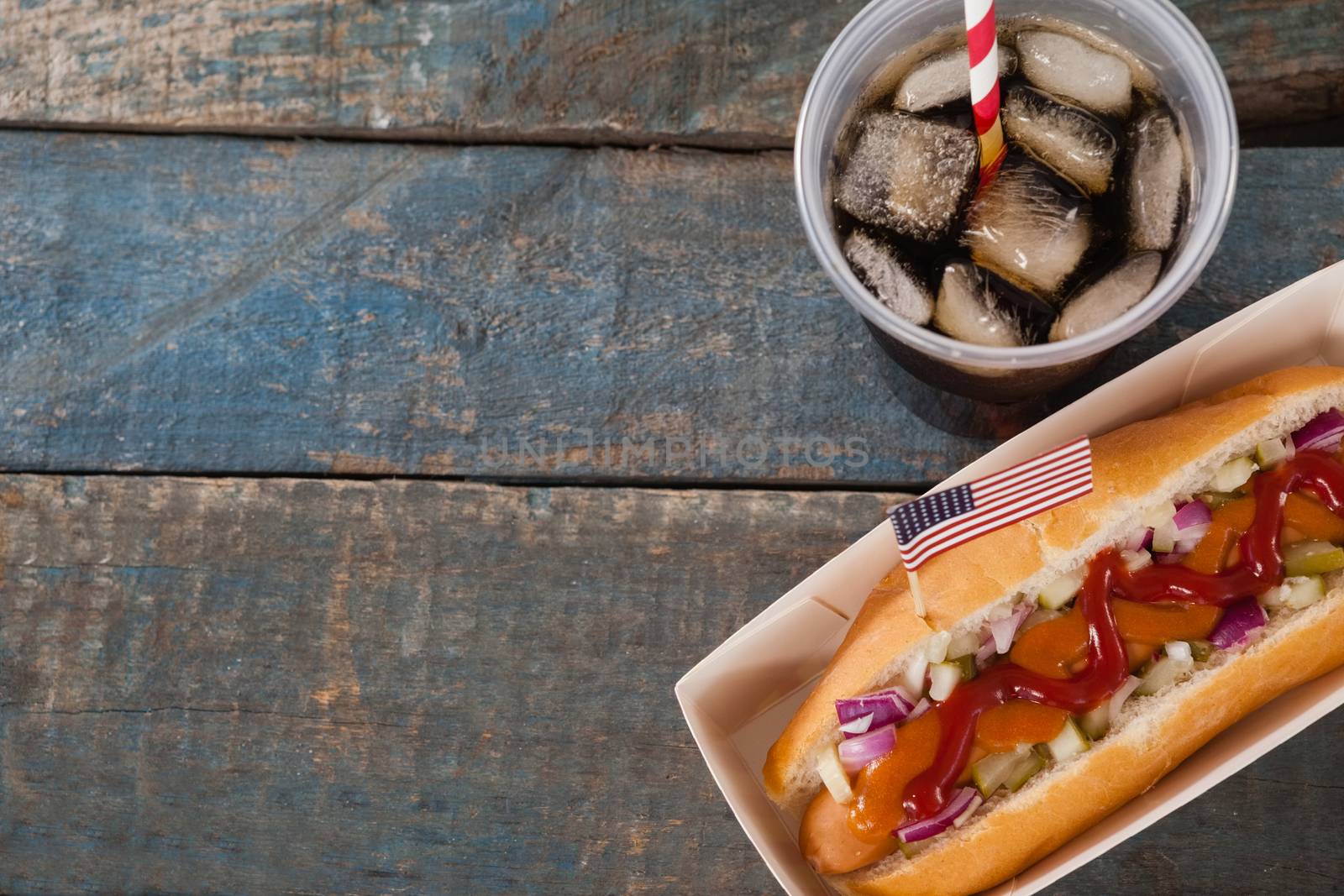 Hot dog and cold drink on with 4th july theme on wooden table