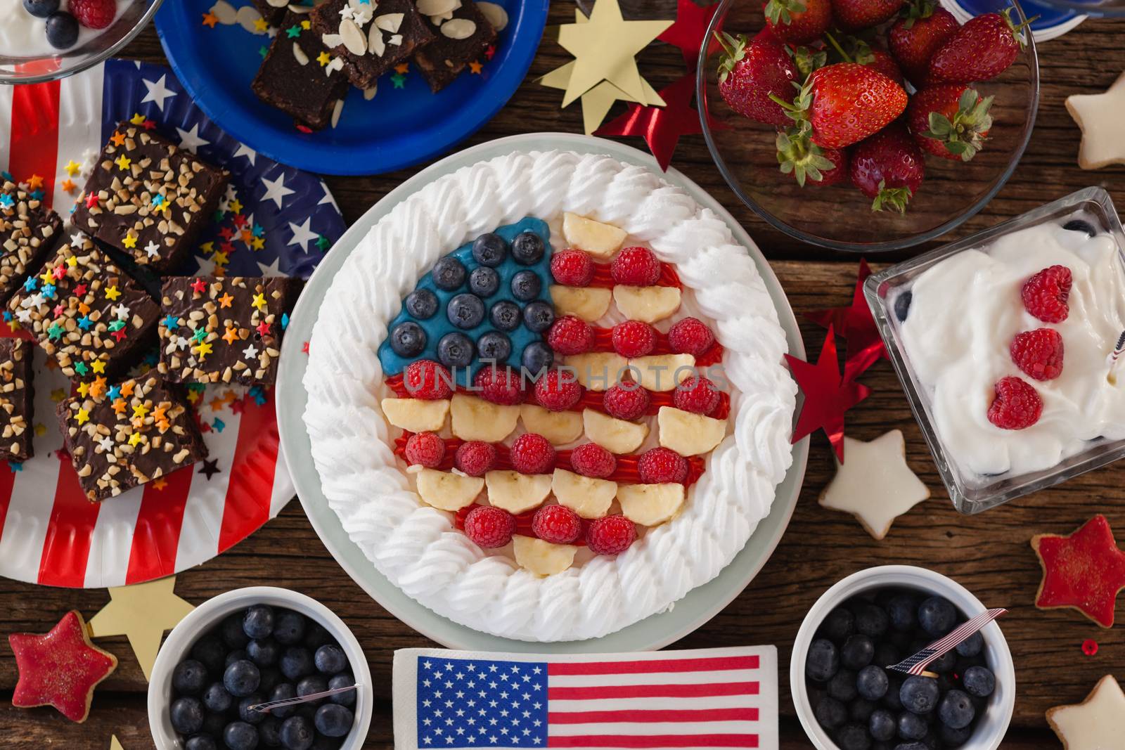 Fruitcake and various sweet foods arranged on wooden table with 4th July theme