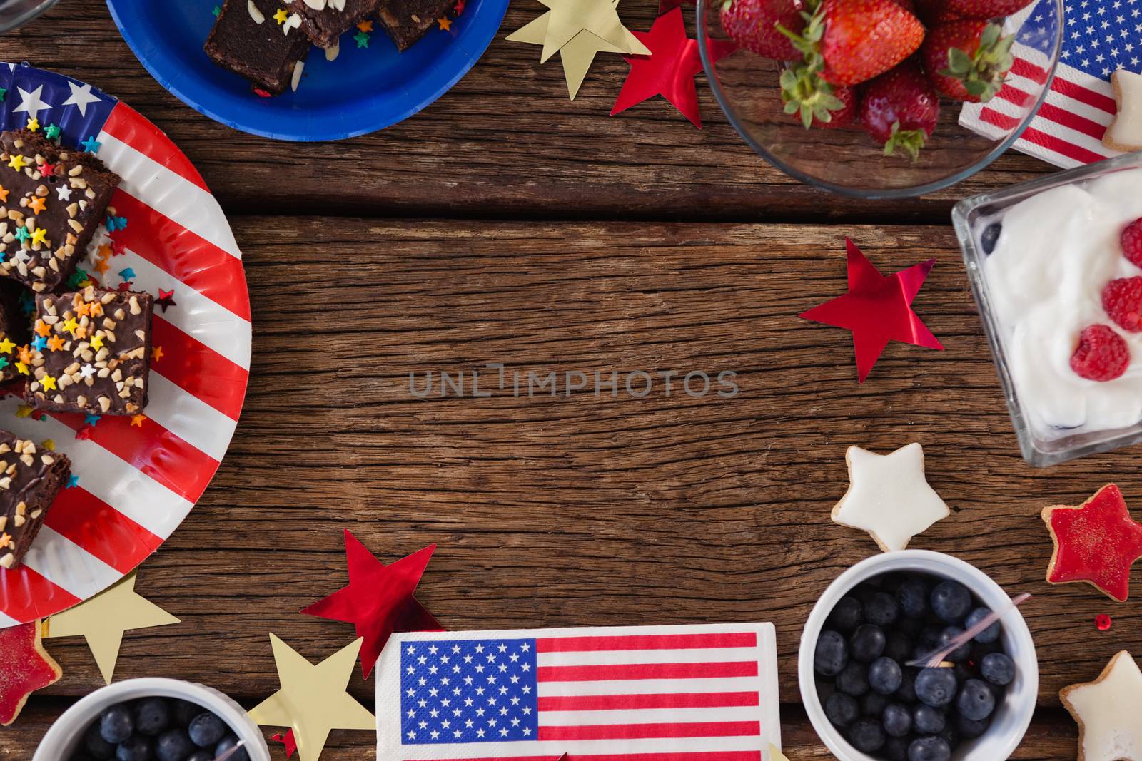 Various sweet foods and fruits arranged on wooden table with 4th July theme