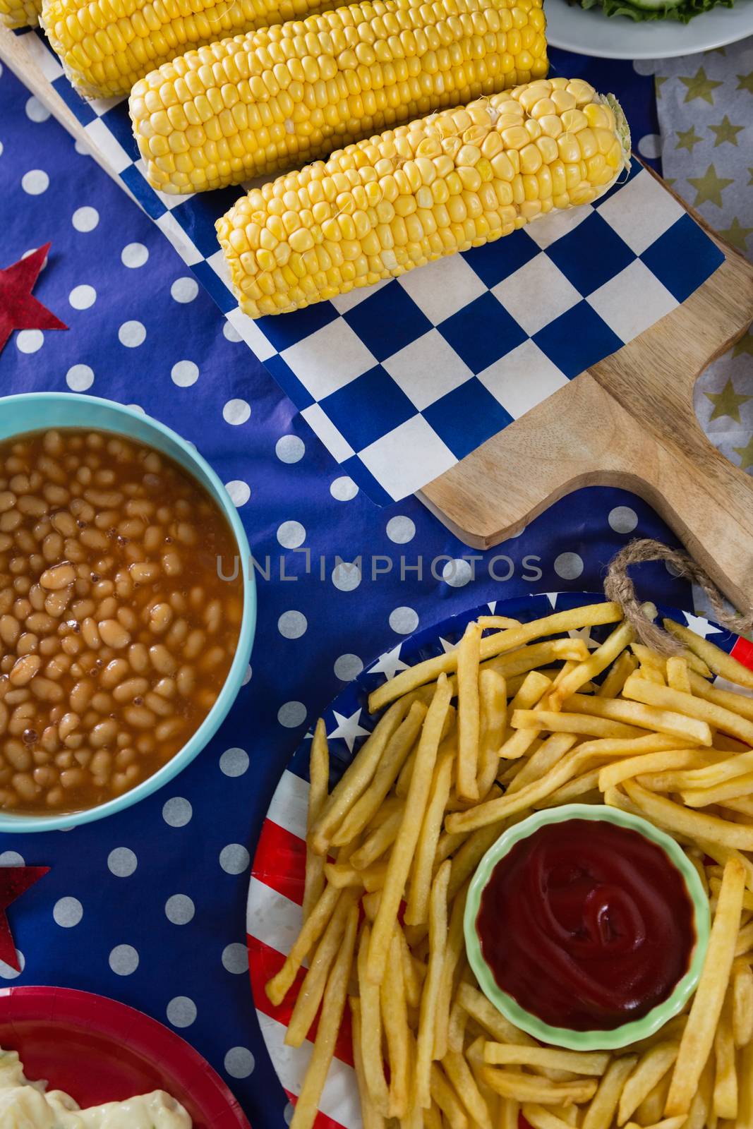 French fries and corn cob on wooden table with 4th july theme by Wavebreakmedia