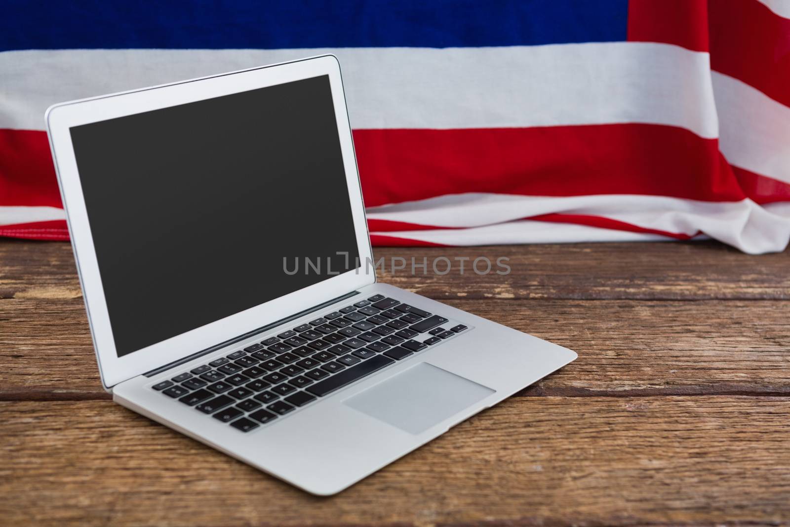 Laptop and American flag on wooden table by Wavebreakmedia