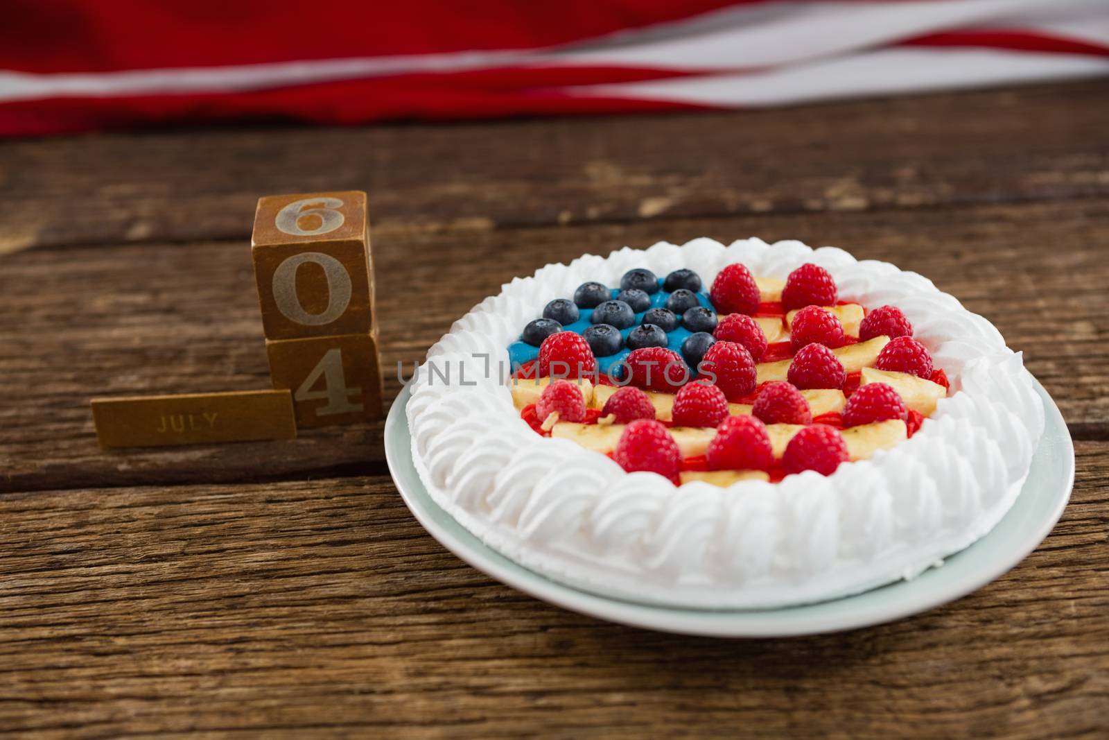 Date blocks and fruitcake on wooden table with 4th july theme by Wavebreakmedia