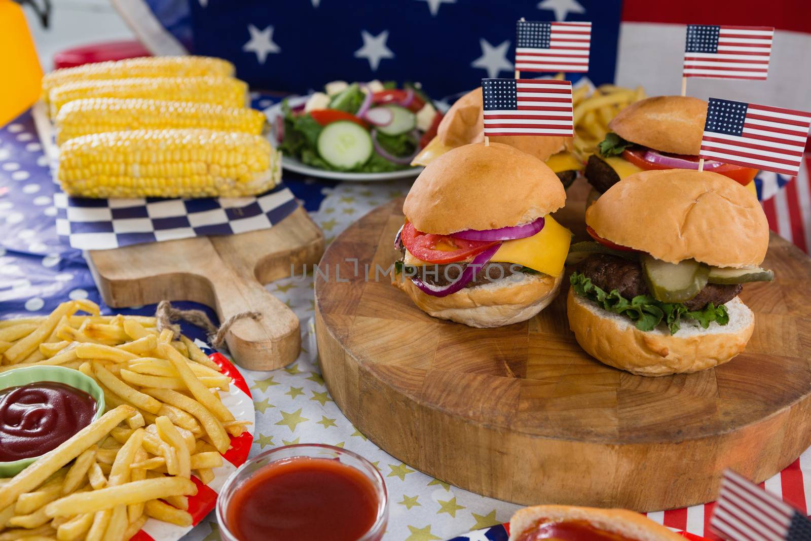 Burgers and corn cob on wooden table with 4th july theme by Wavebreakmedia