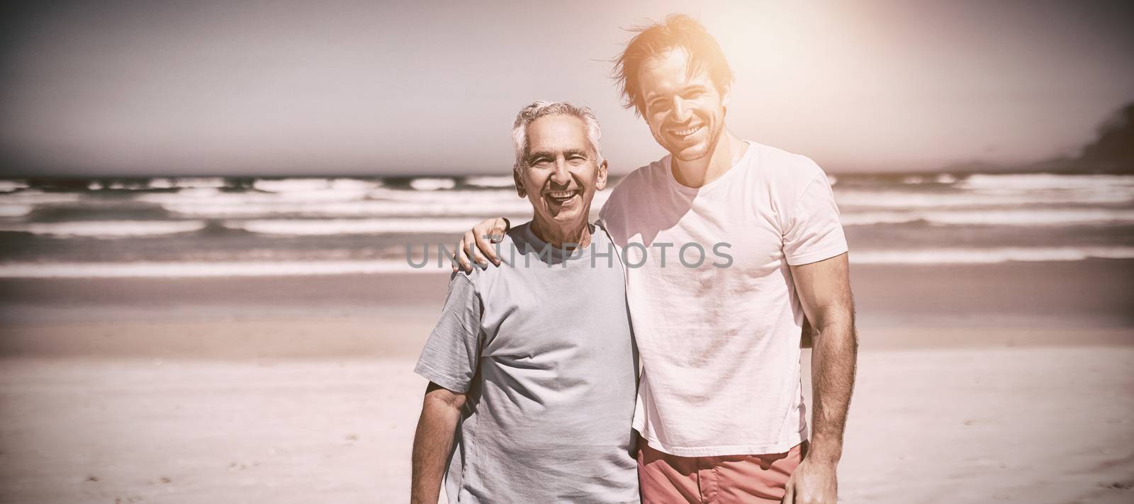 Portrait of smiling family standing at beach during sunny day