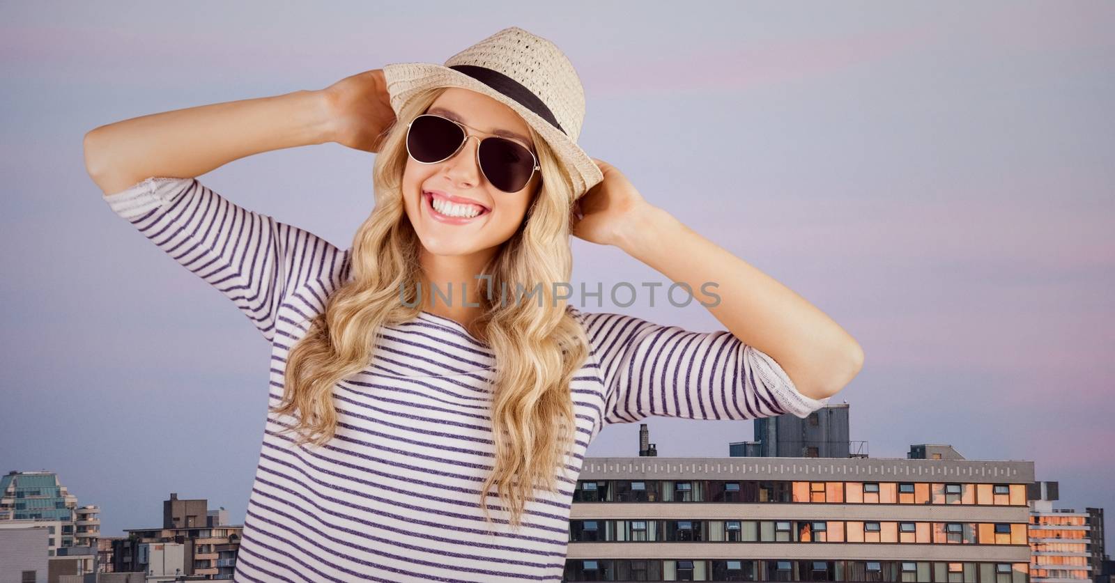 Digital composite of Woman in summer clothes with hands on head against buildings and evening sky