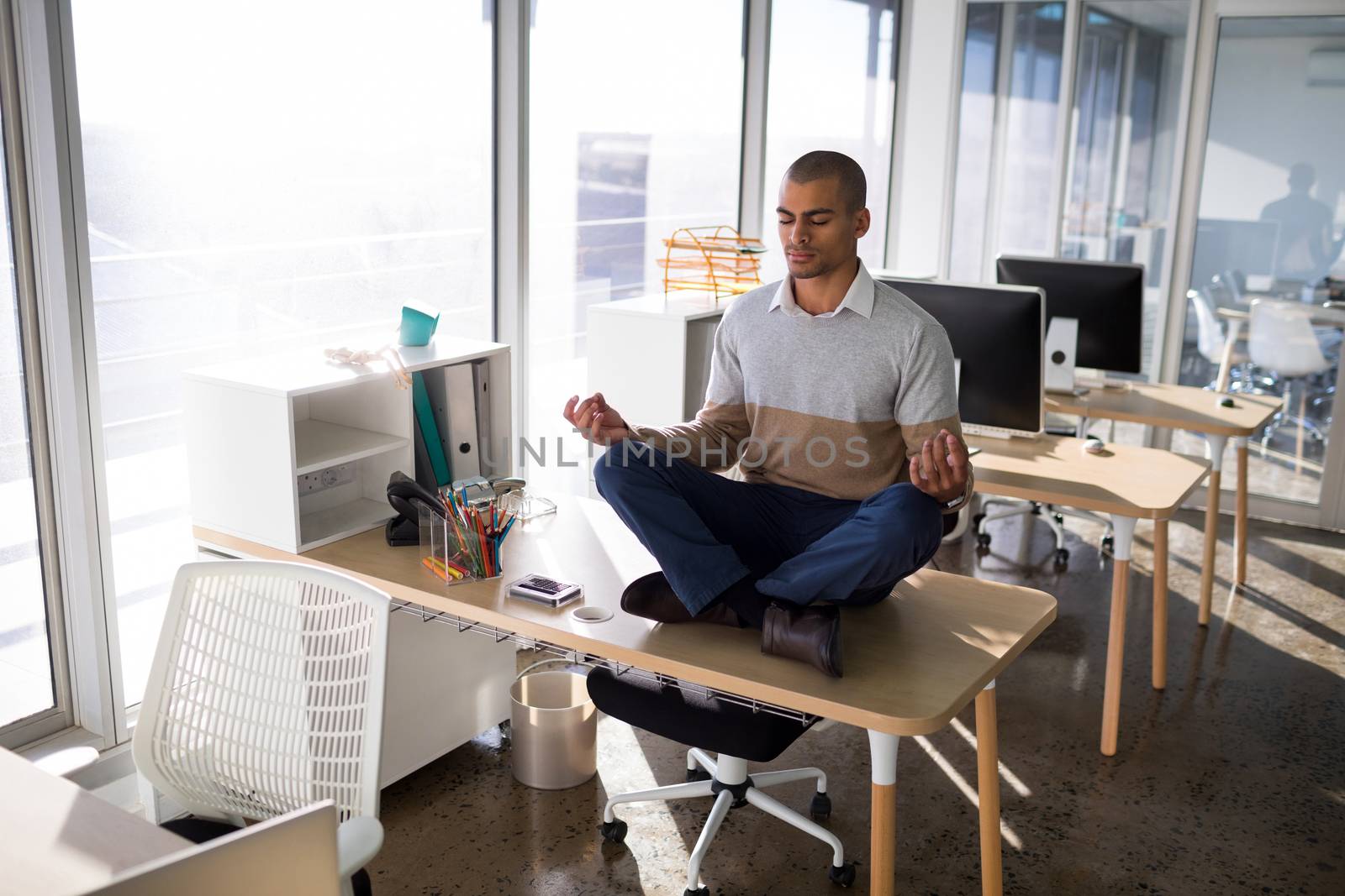 Male executive doing yoga on desk in office