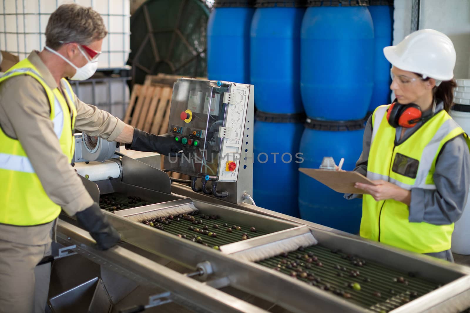Technicians operating machine while processing olives by Wavebreakmedia