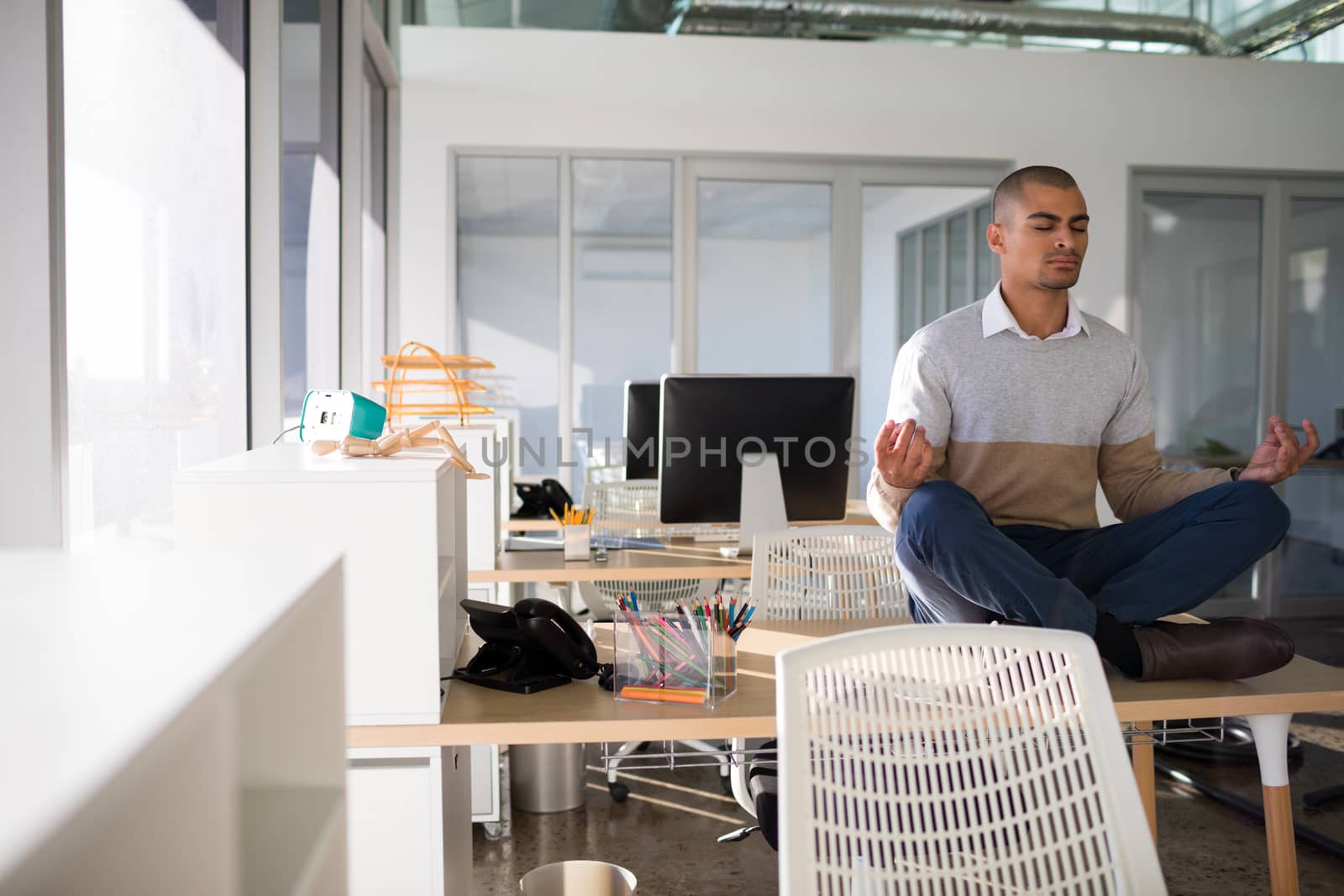 Male executive doing yoga on desk in office