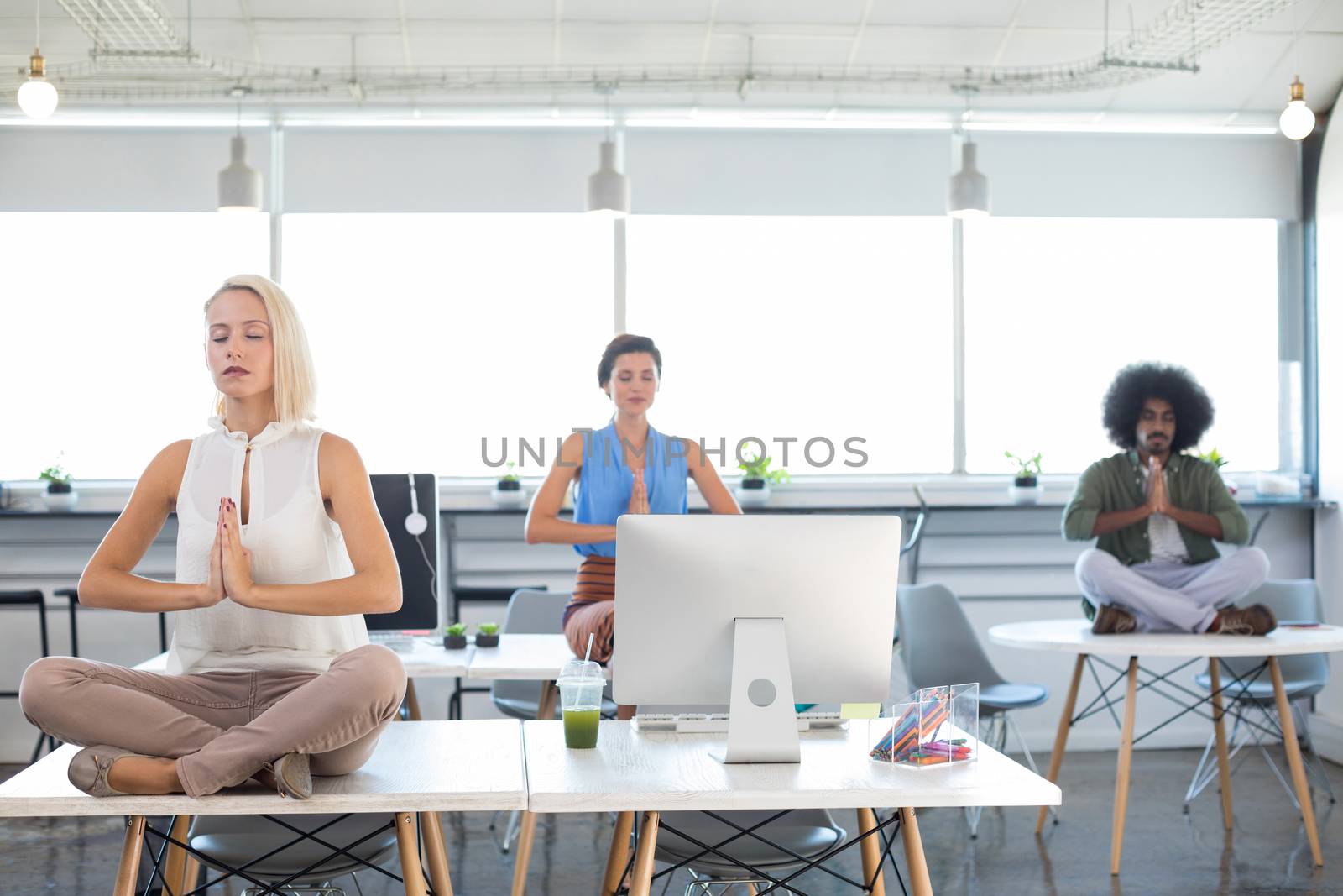 Executives doing yoga in office by Wavebreakmedia