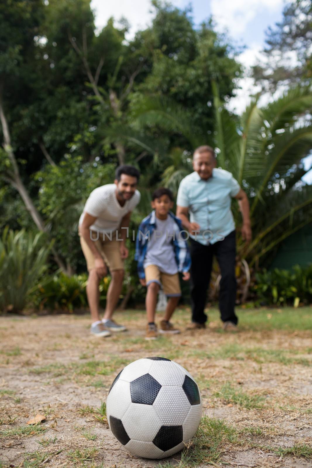 Family looking at soccer ball while playing in yard