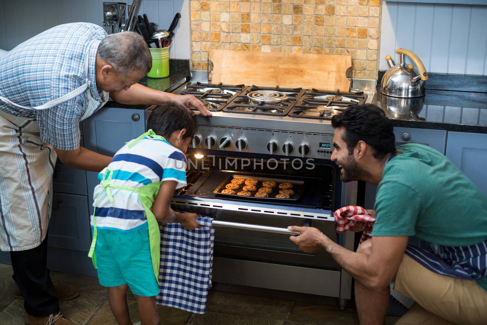 Family keeping cookies in oven at home