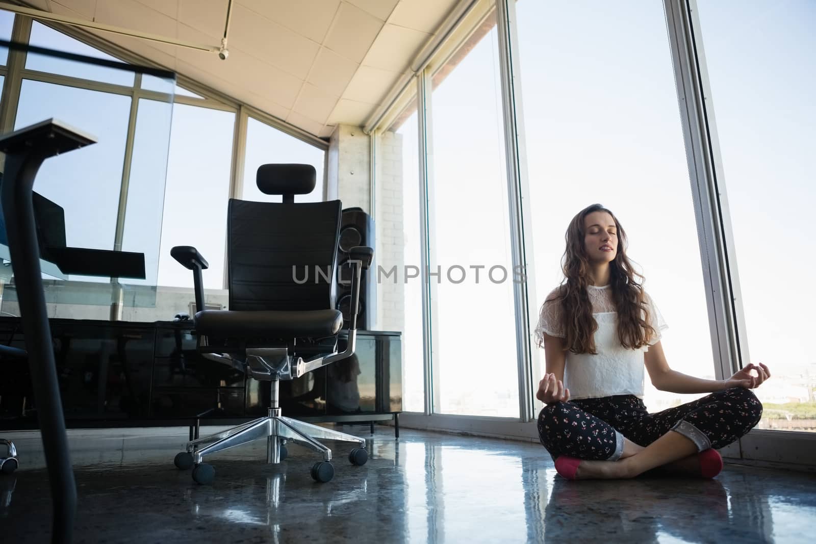 Young businesswoman doing yoga on floor by Wavebreakmedia