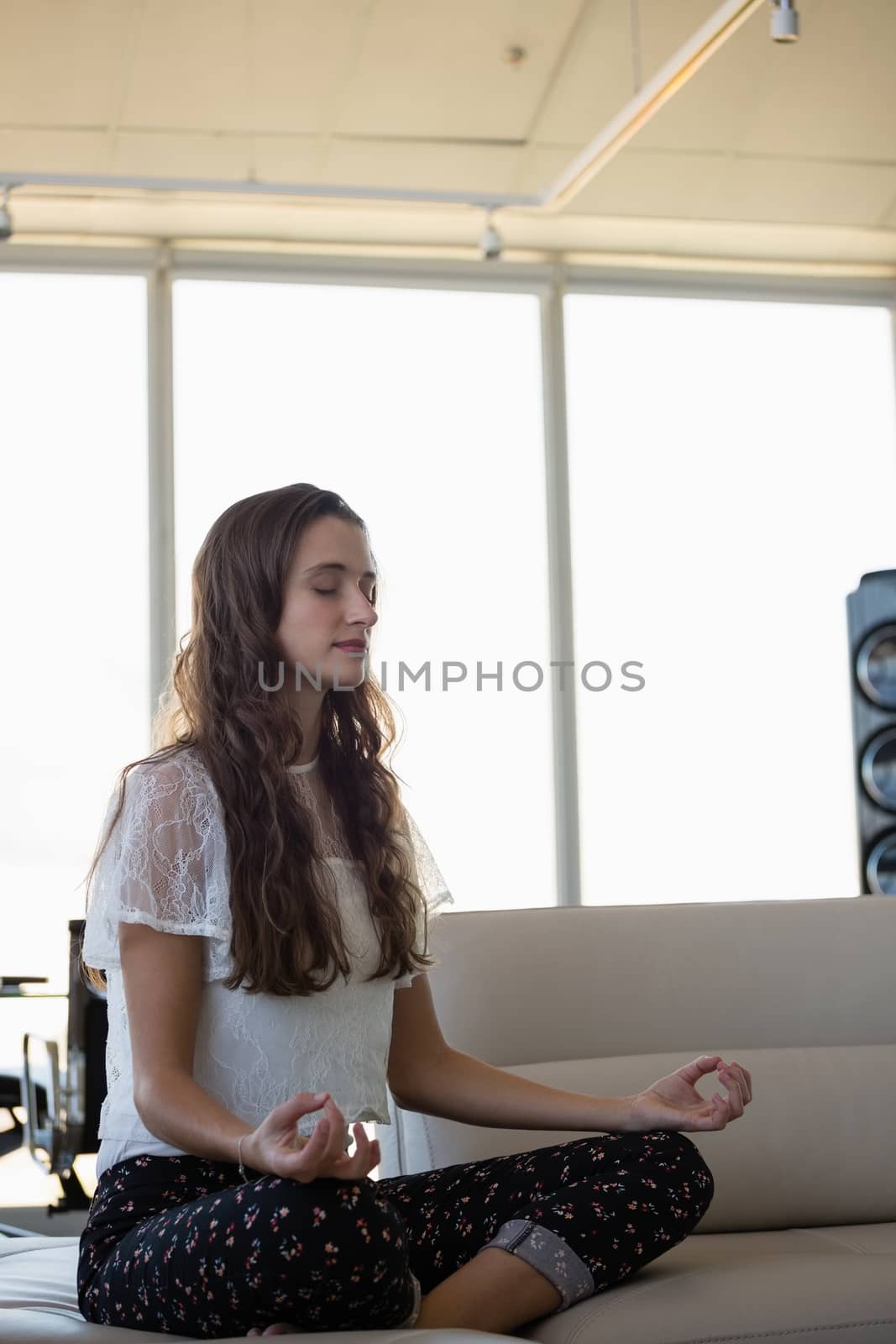 Young woman doing yoga in office by Wavebreakmedia