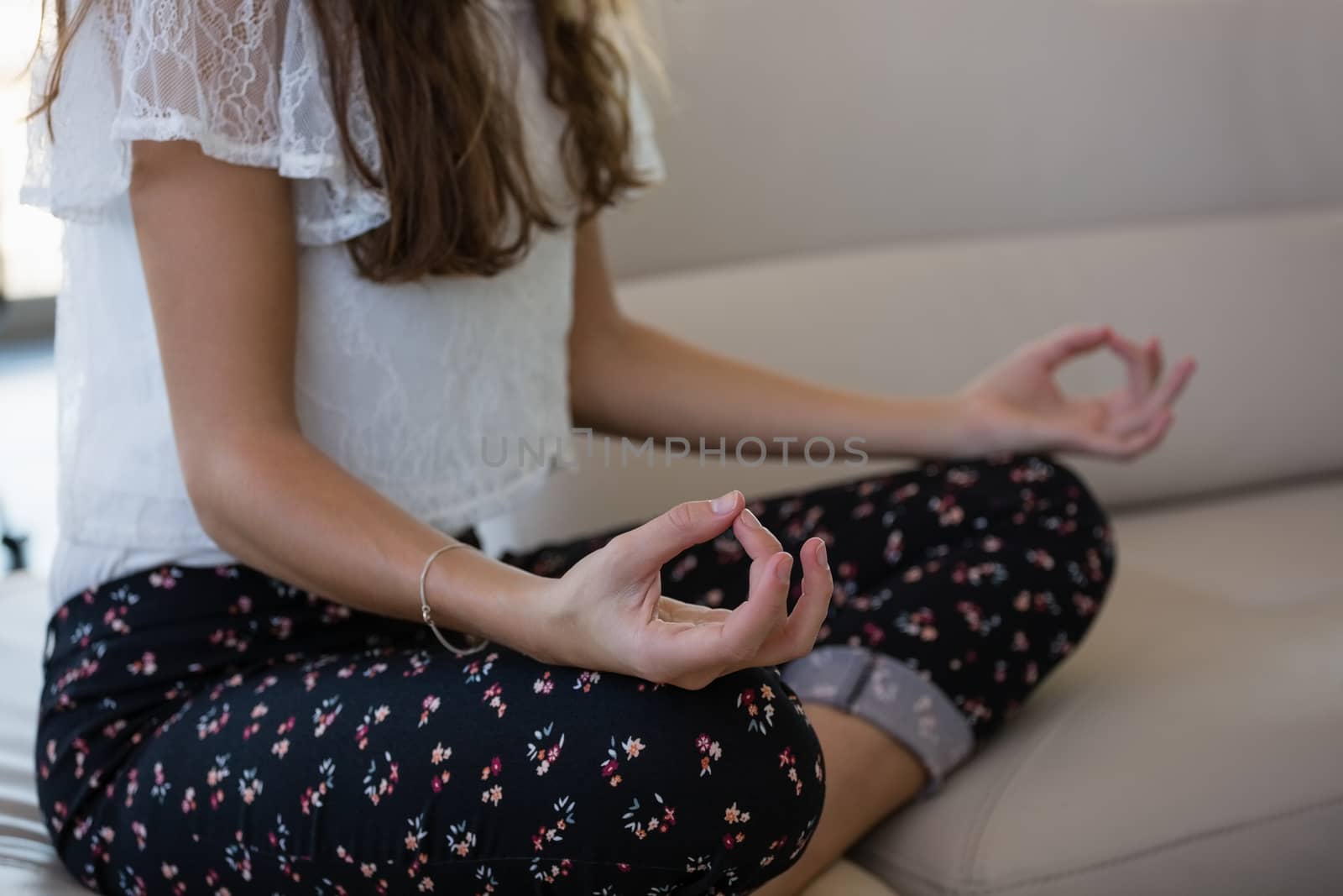 Midsection of businesswoman doing yoga while sitting on sofa in office