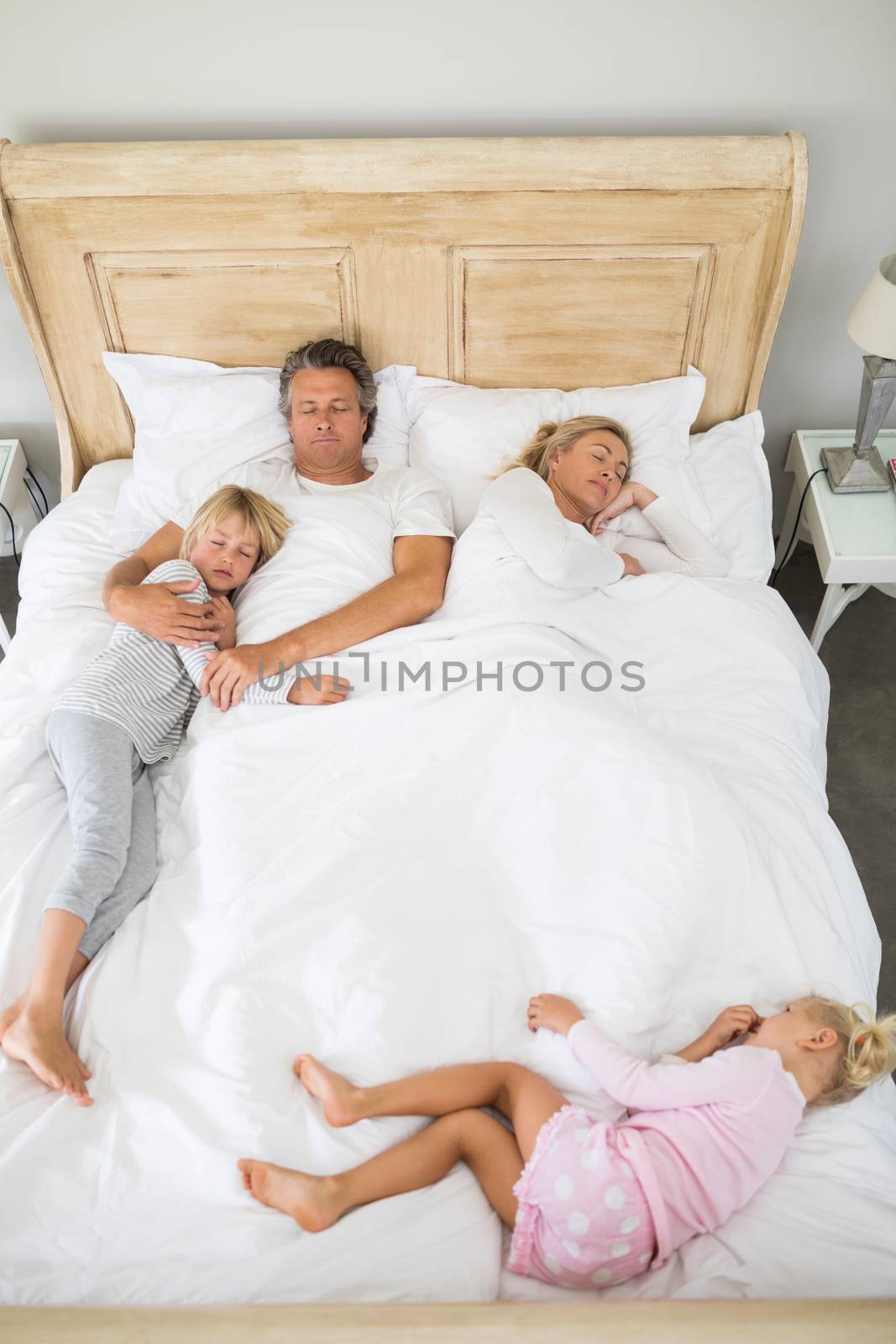 Family sleeping on bed in the bed room by Wavebreakmedia