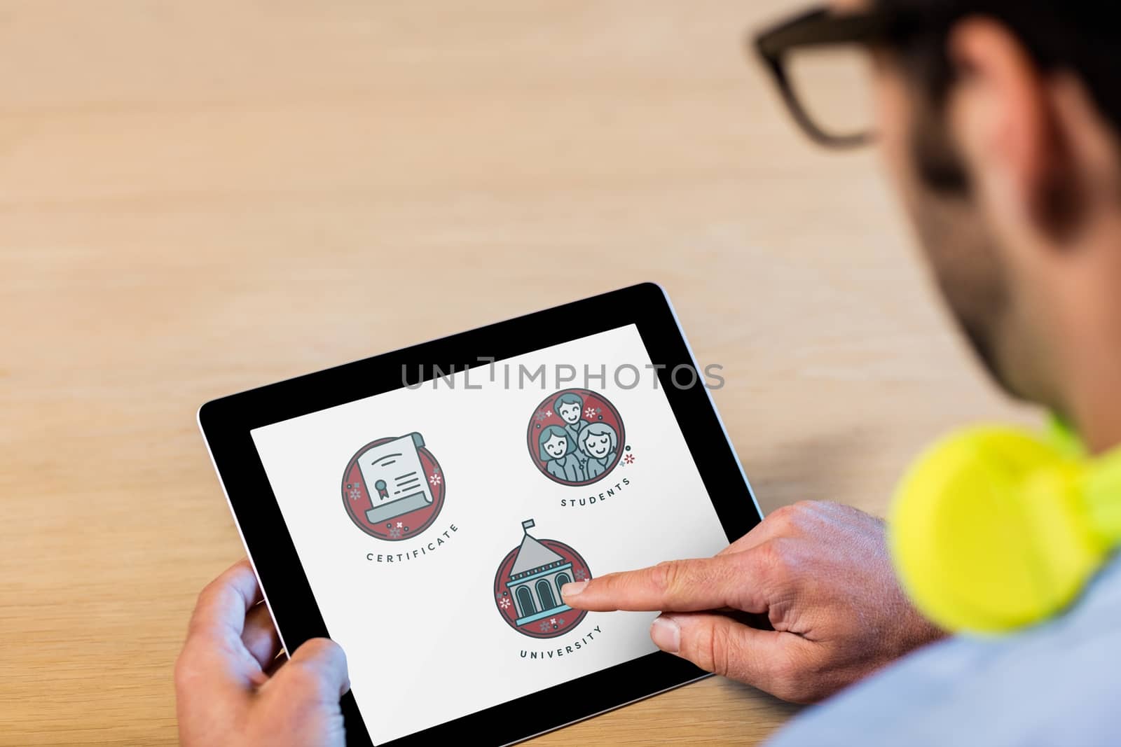Digital composite of Man using a tablet with education icons on the screen