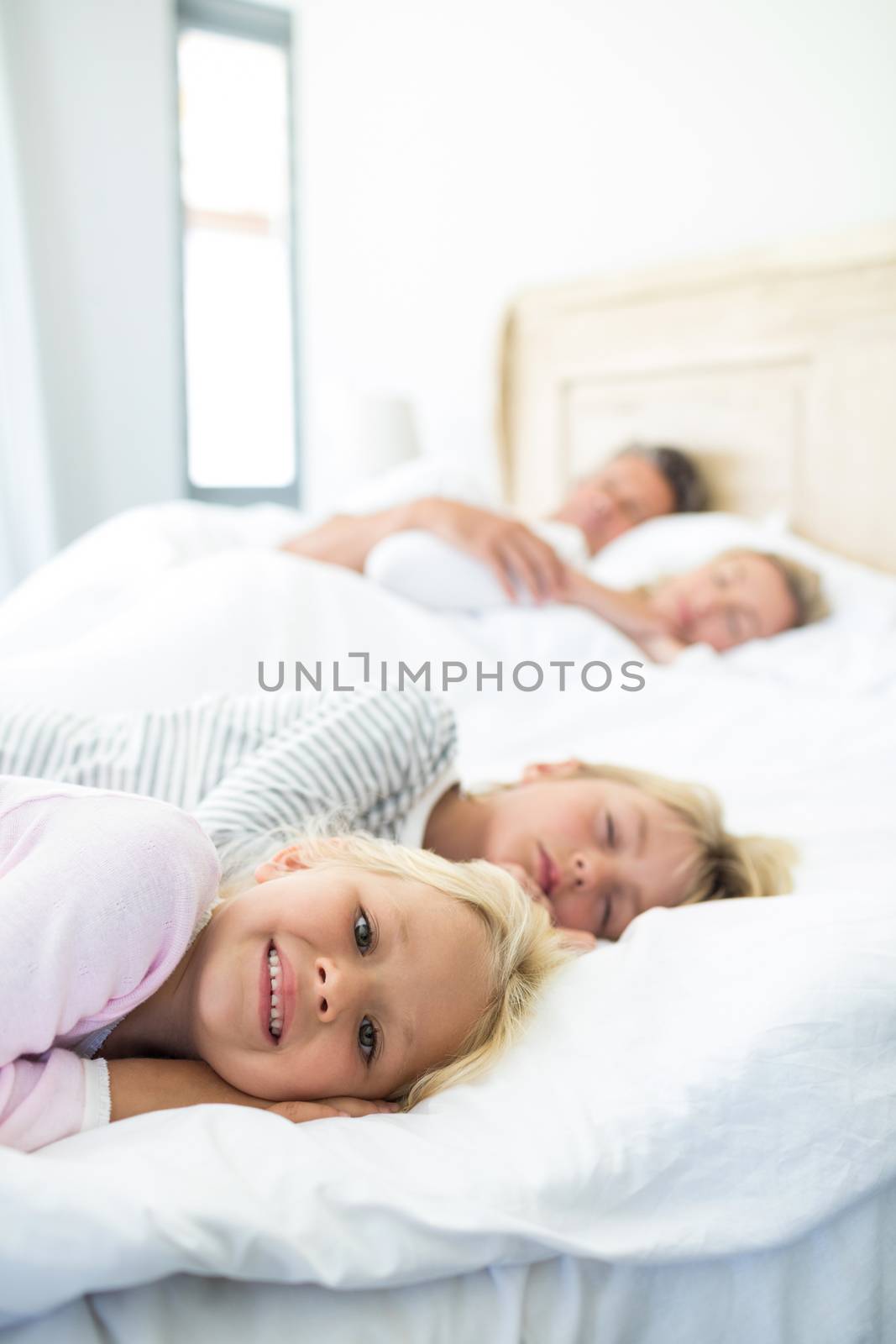 Family sleeping on bed in the bed room by Wavebreakmedia