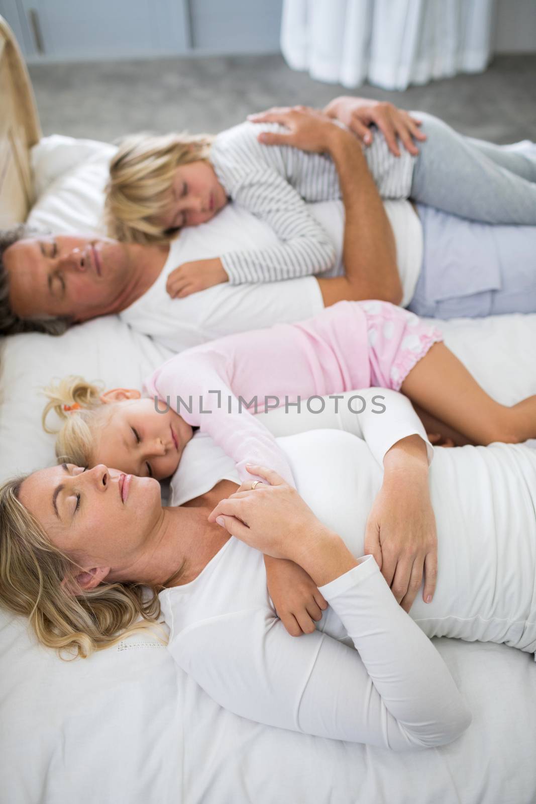 Family sleeping on bed in the bed room at home