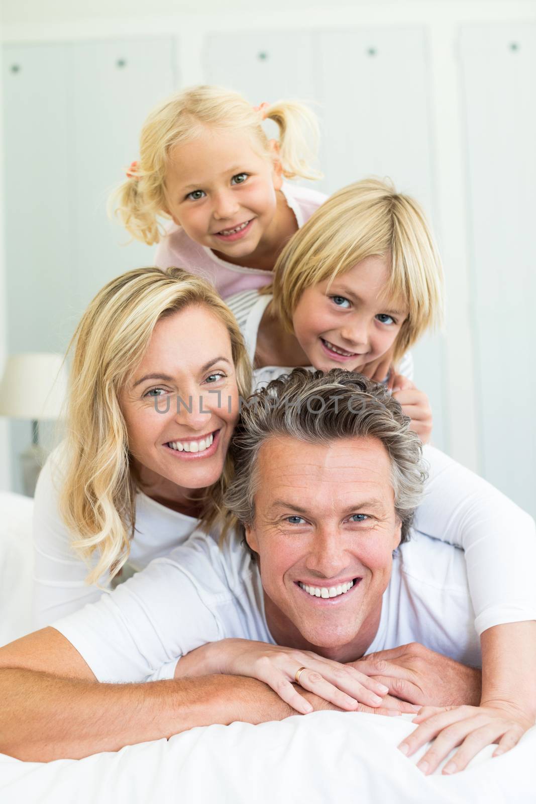 Happy family having fun on bed in the bed room by Wavebreakmedia