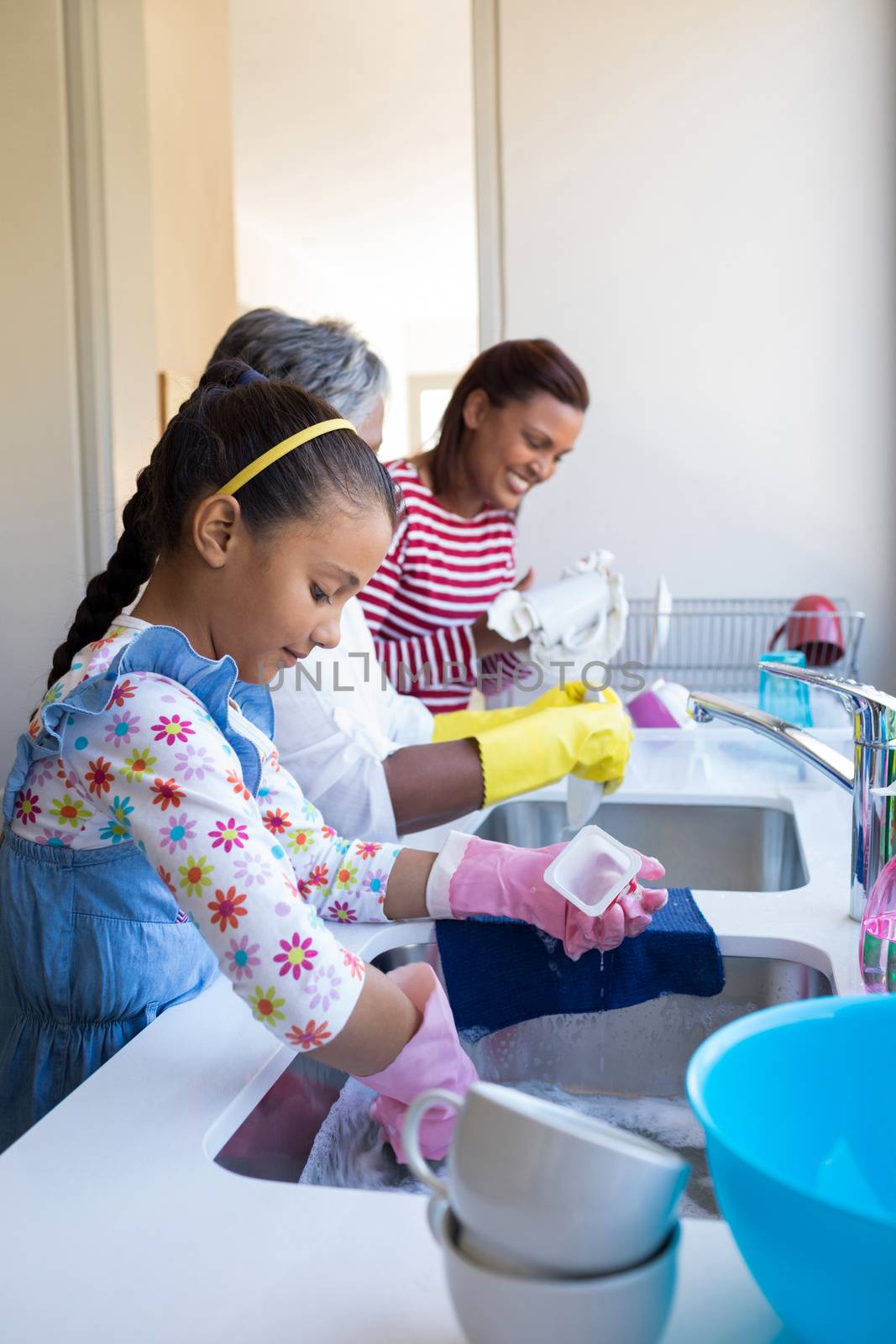 Family washing utensils in kitchen sink at home