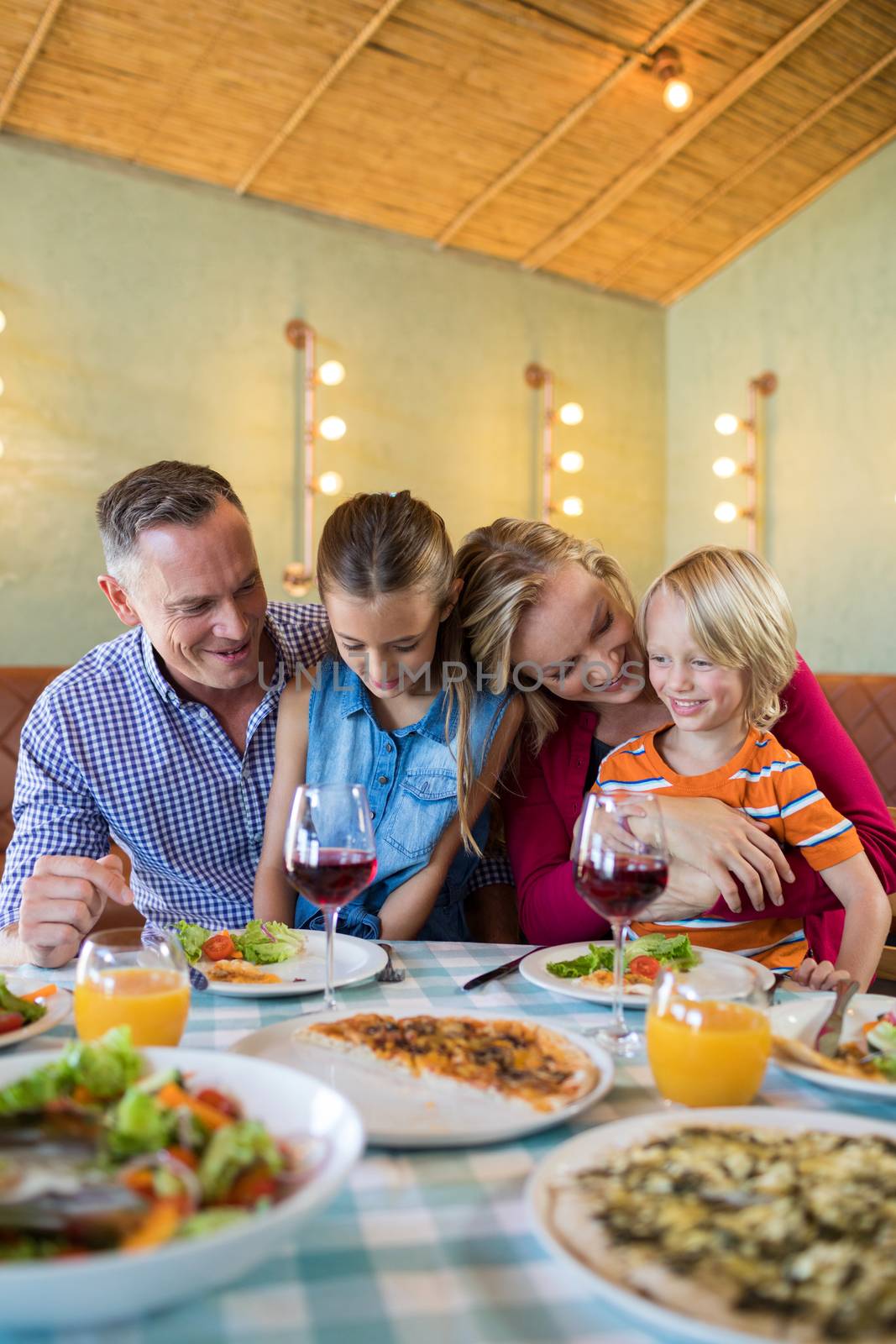 Happy family enjoying dinner at restaurant by Wavebreakmedia