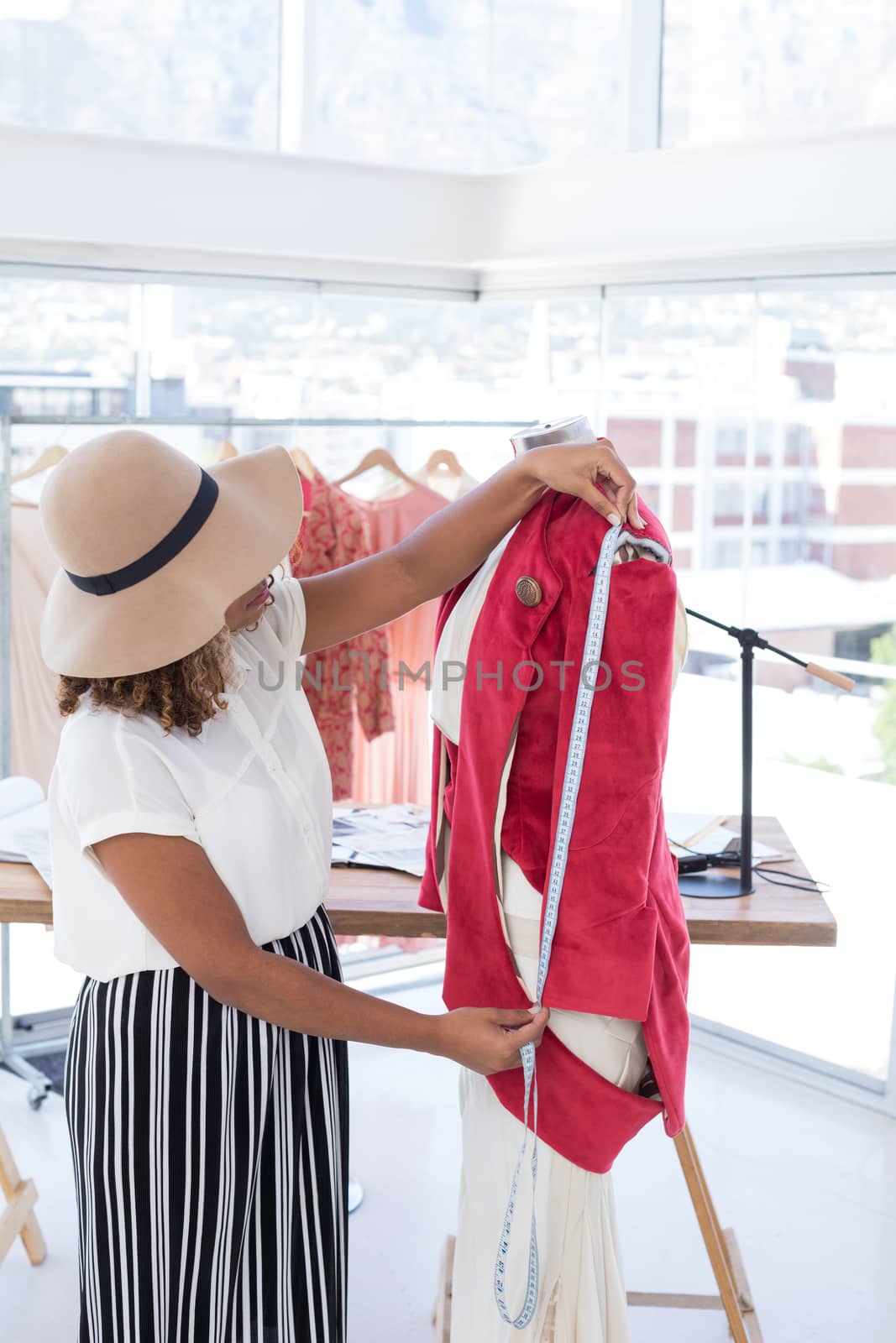 Fashion designer taking a measurement from measuring tape in office