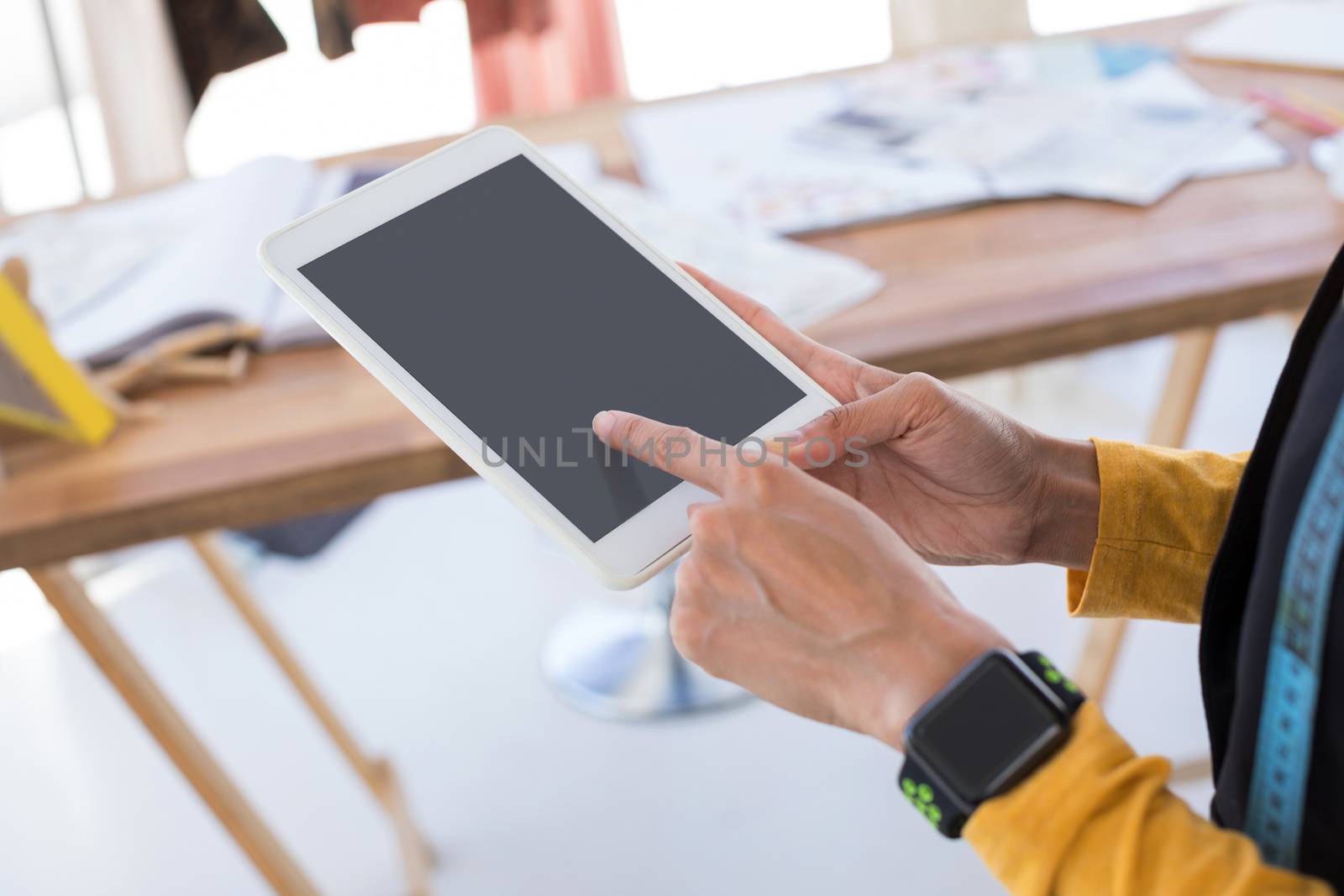 Mid-section of fashion designer using digital tablet in office