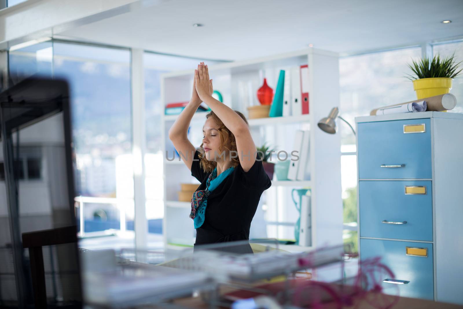 Female executive doing yoga on desk in office