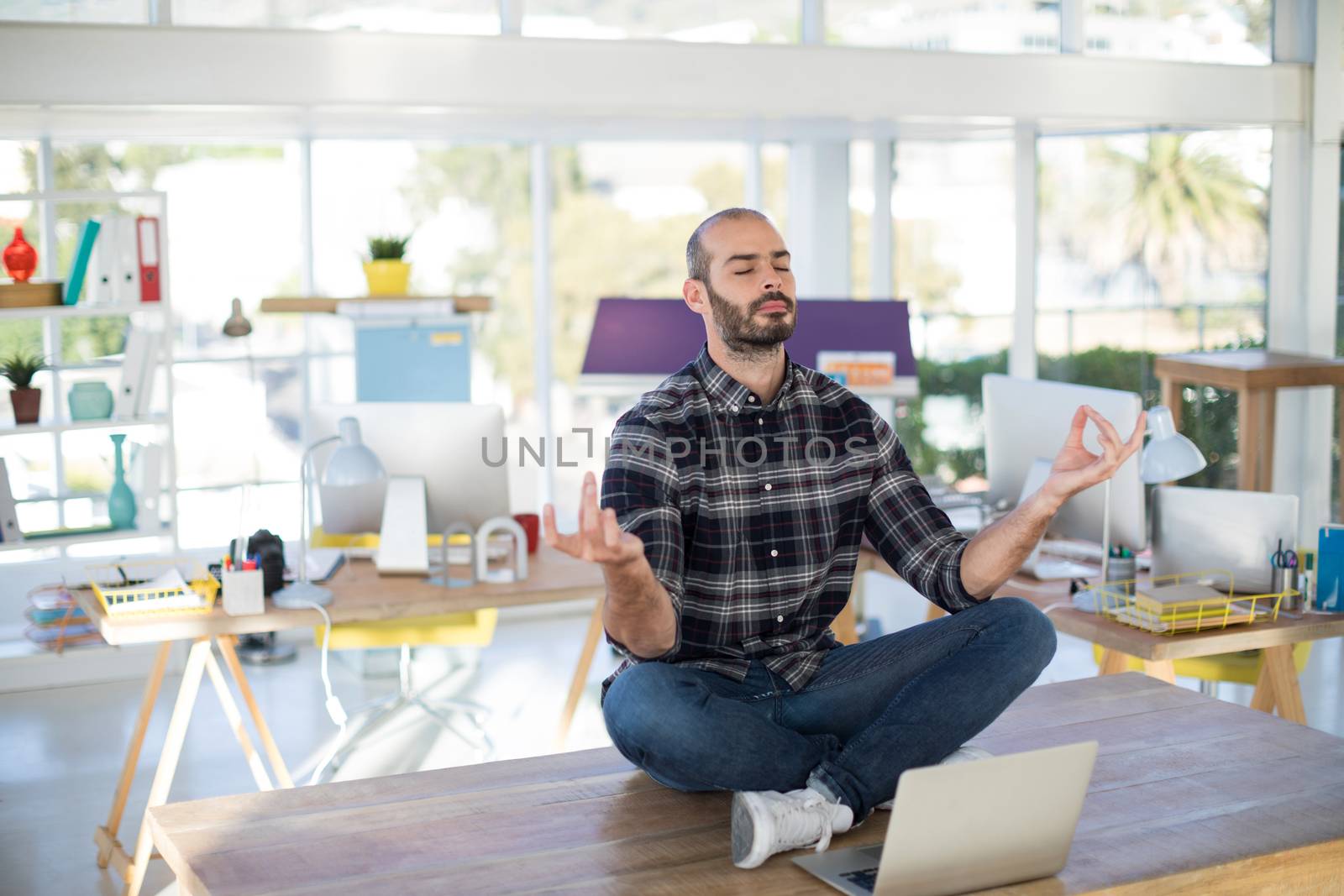 Male executive doing yoga on desk in office
