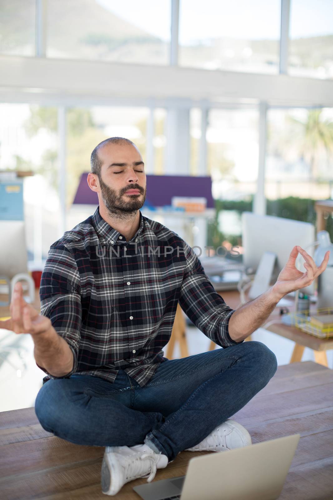 Male executive doing yoga in office by Wavebreakmedia