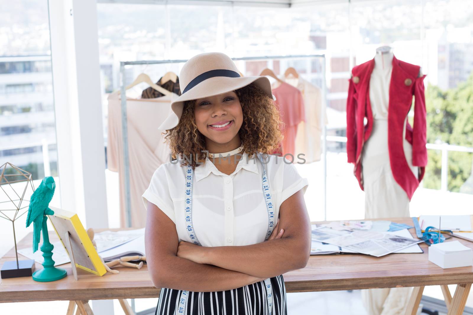 Portrait of smiling fashion designer standing with arms crossed in office