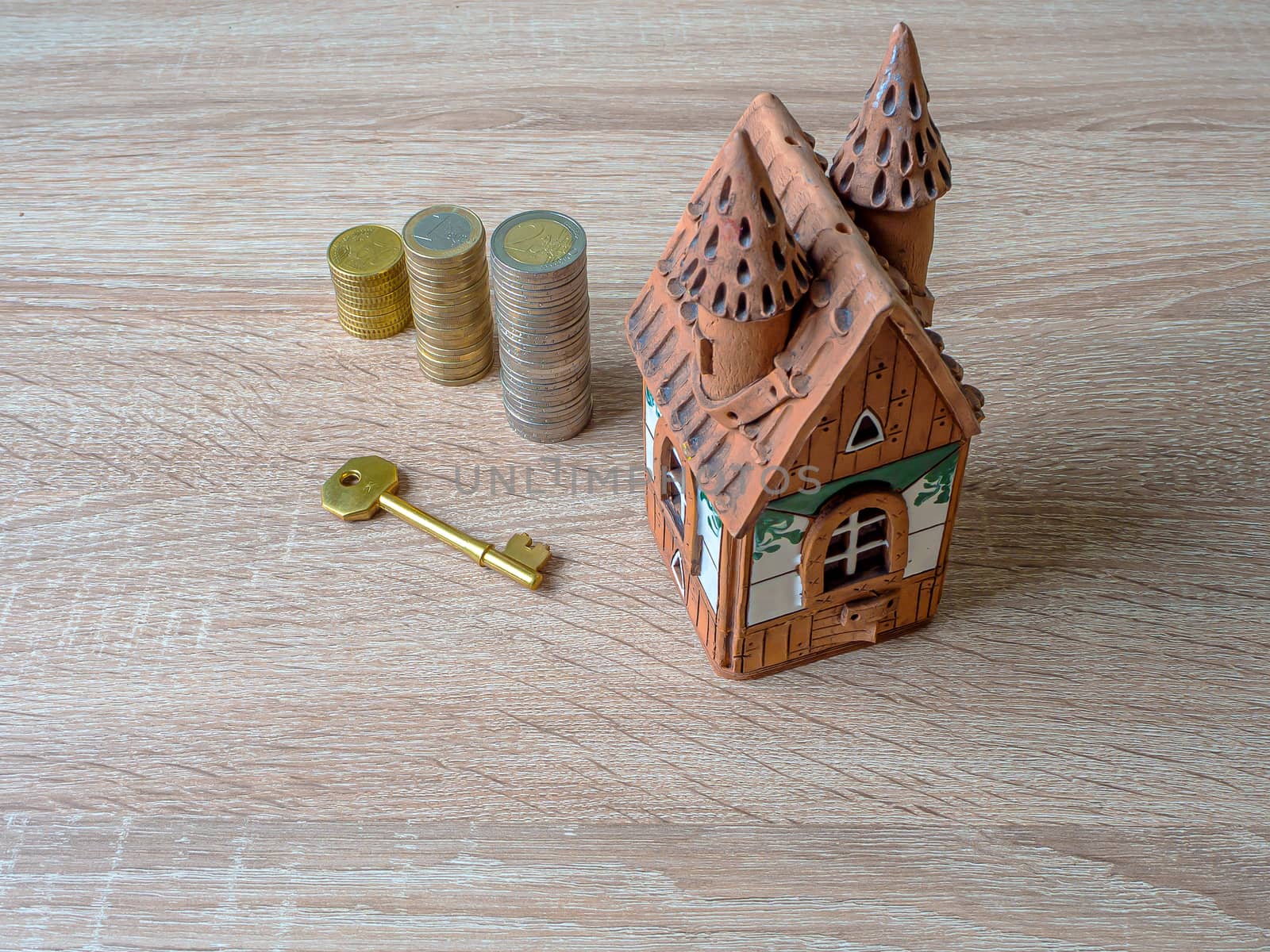 Model of a house, Stack of European Euro coins and golden key On Wooden Table. Real estate agency, mortgage loan, lottery, buying property.Home loan and investment concept. Copy space