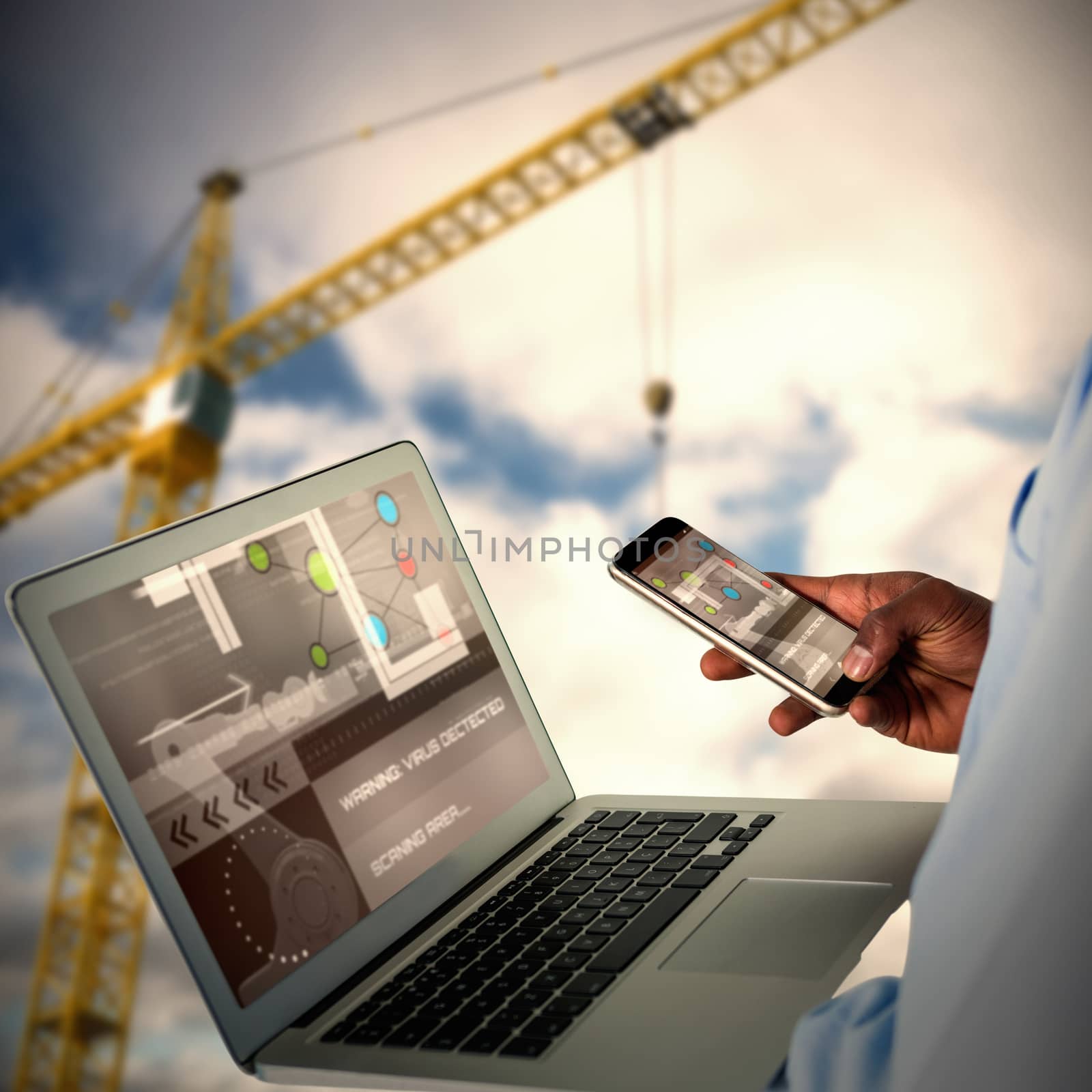 Businessman using mobile phone and laptop against 3d image of yellow crane against cloudy sky