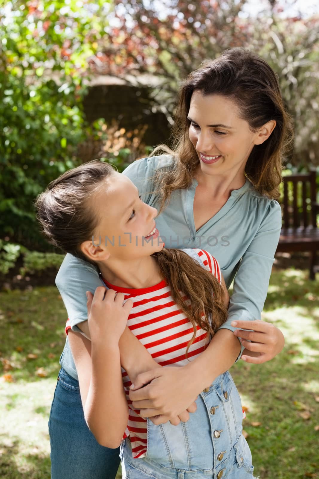 Smiling woman and daughter enjoying at backyard during summer