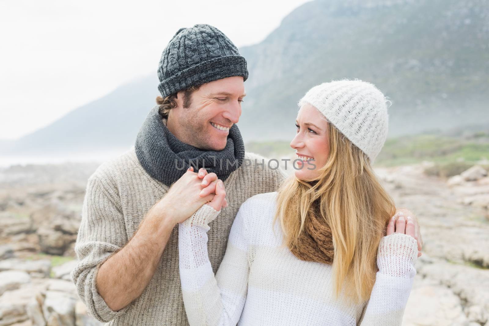 Happy romantic young couple standing together on a rocky landscape