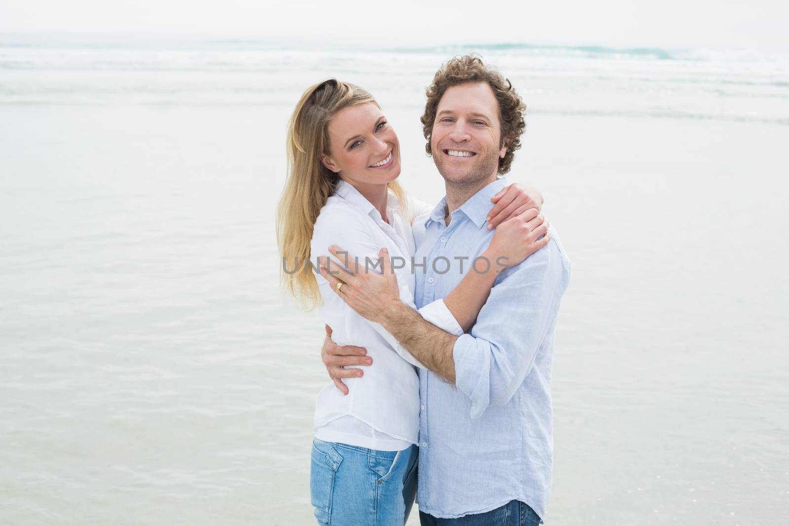 Happy romantic couple embracing at beach by Wavebreakmedia